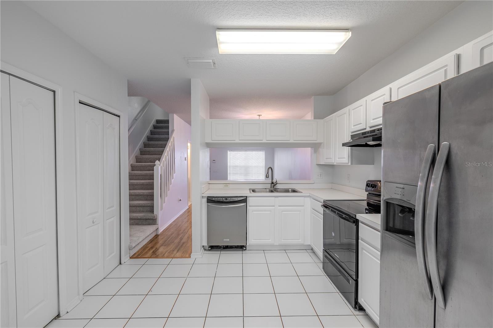 The kitchen features neutral tone cabinets and countertops, and a stainless steel dishwasher. There is a laundry closet with washer/dryer.