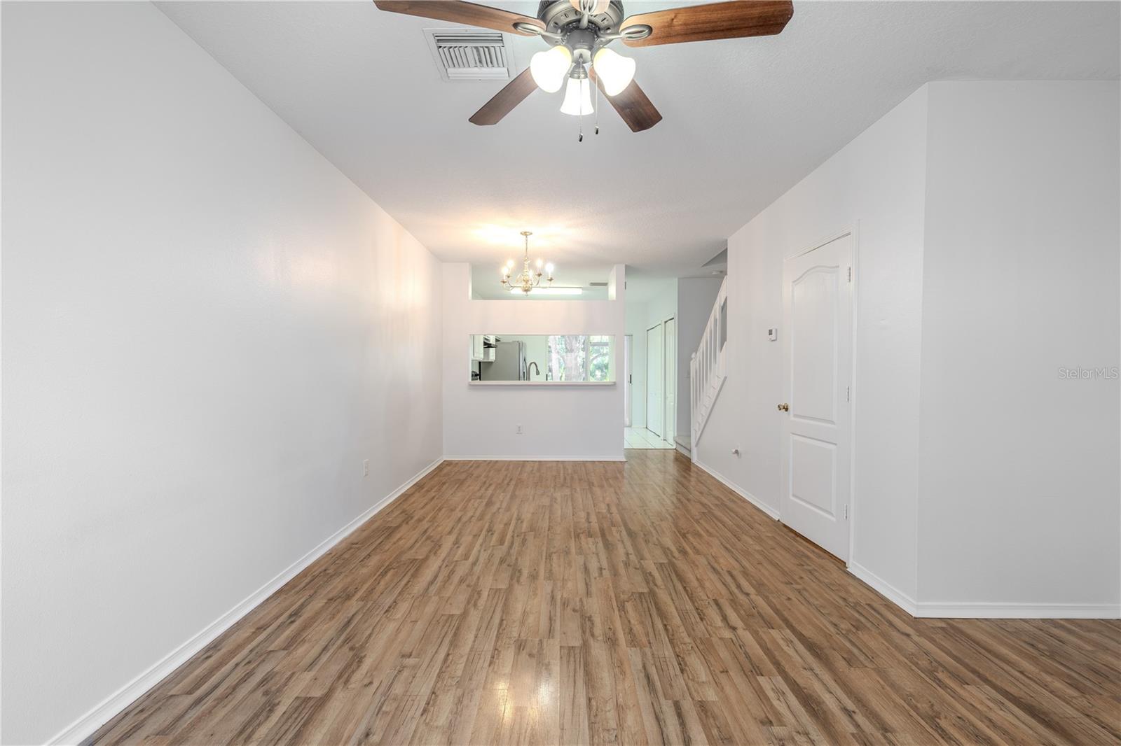 The Living room features neutral tones, wood laminate flooring, a ceiling fan with light kit and picture window.