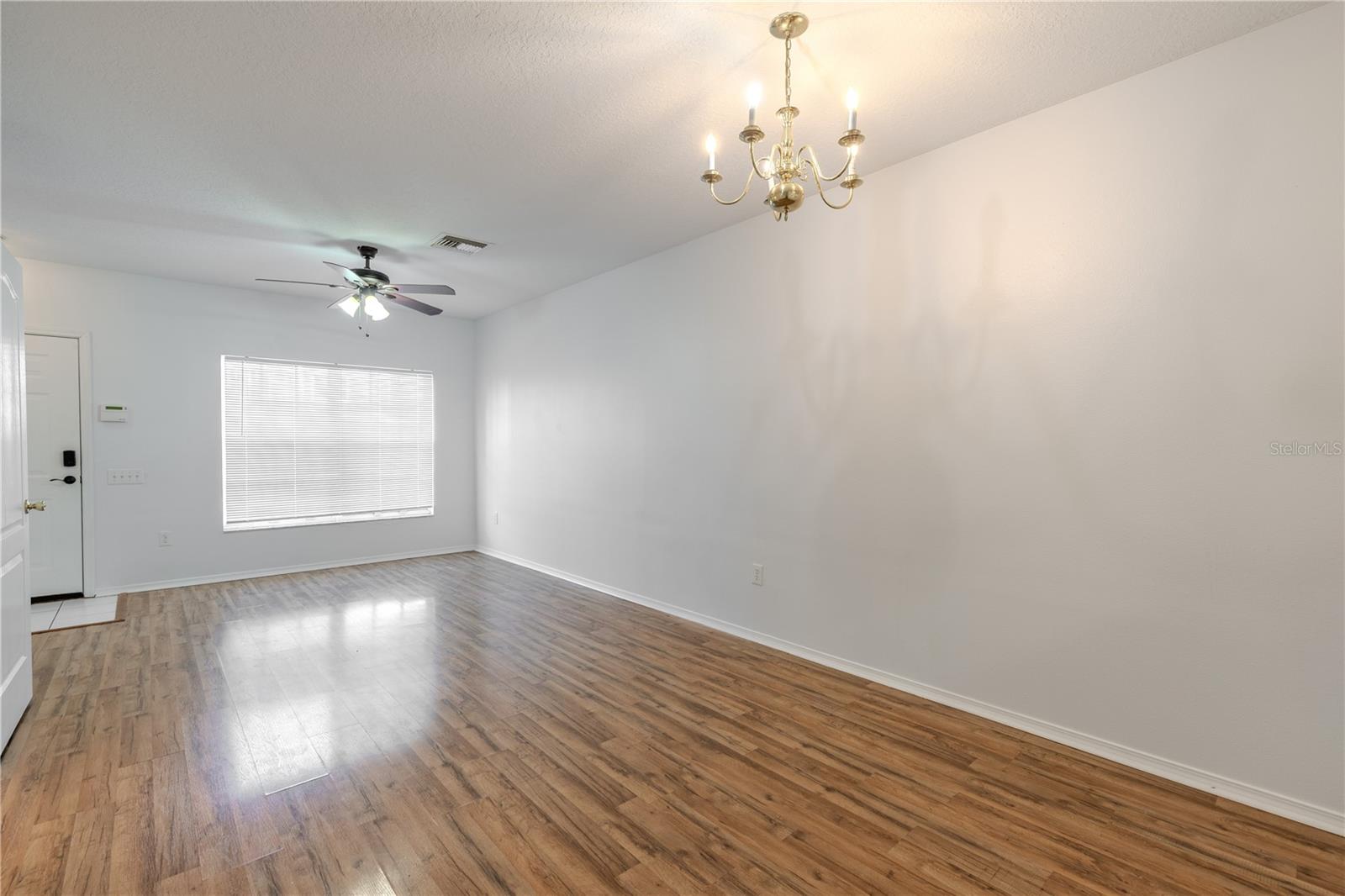 The Living room features neutral tones, wood laminate flooring, a ceiling fan with light kit and picture window.