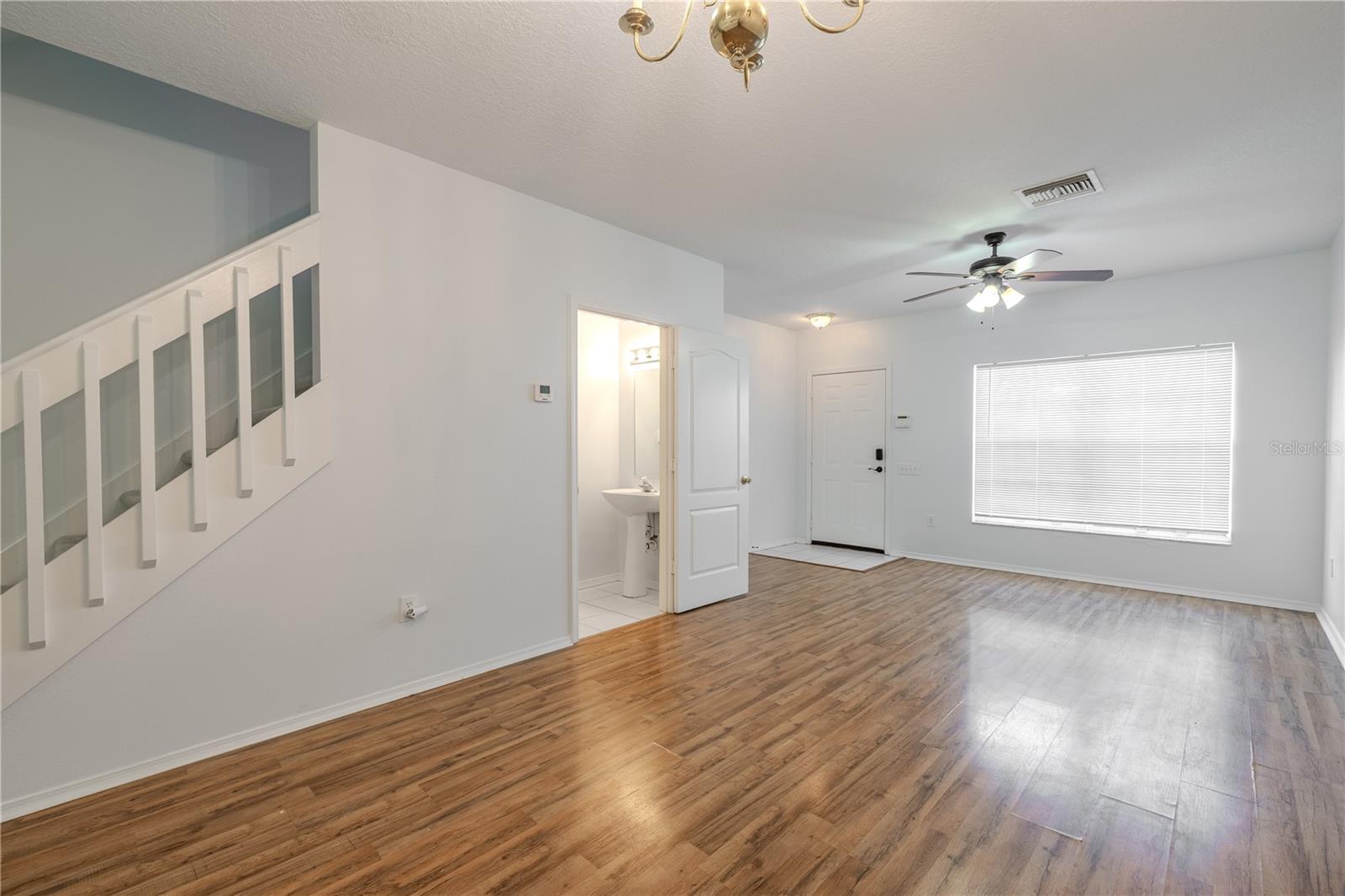 The Living room features neutral tones, wood laminate flooring, a ceiling fan with light kit and picture window.