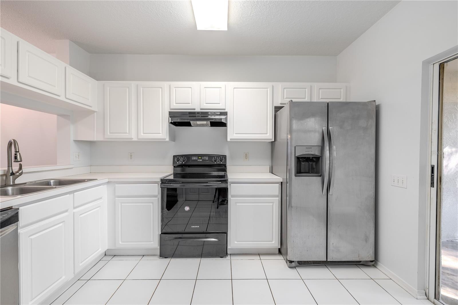 The kitchen features neutral tone cabinets and countertops, and a stainless steel dishwasher. There is a laundry closet with washer/dryer.