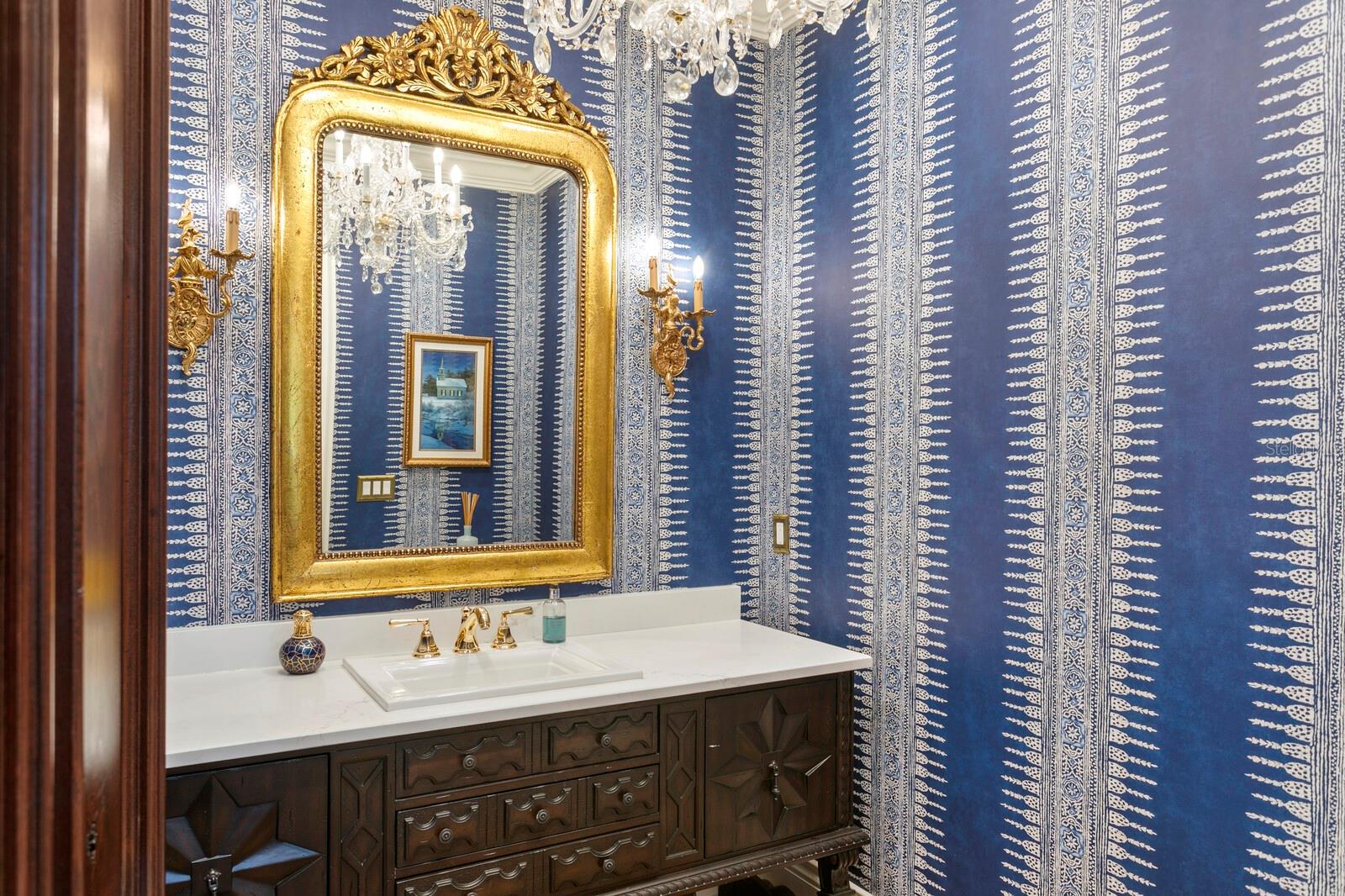 The exquisitely adorned powder room is graced with an opulent, elegantly crafted vanity