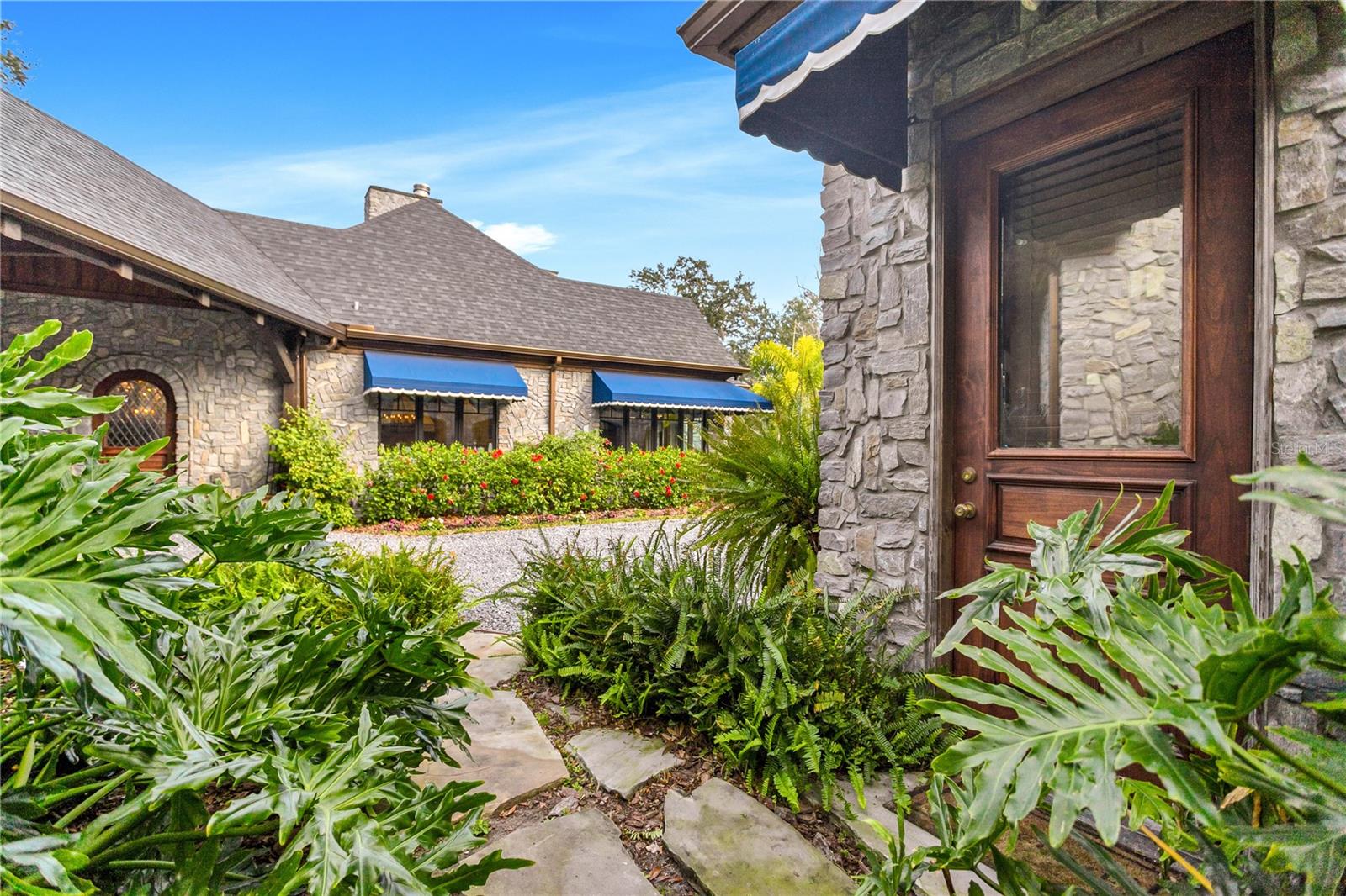 Set amidst lush verdant foliage, the charming facade—adorned with delightful blue awnings—invites you to explore further.