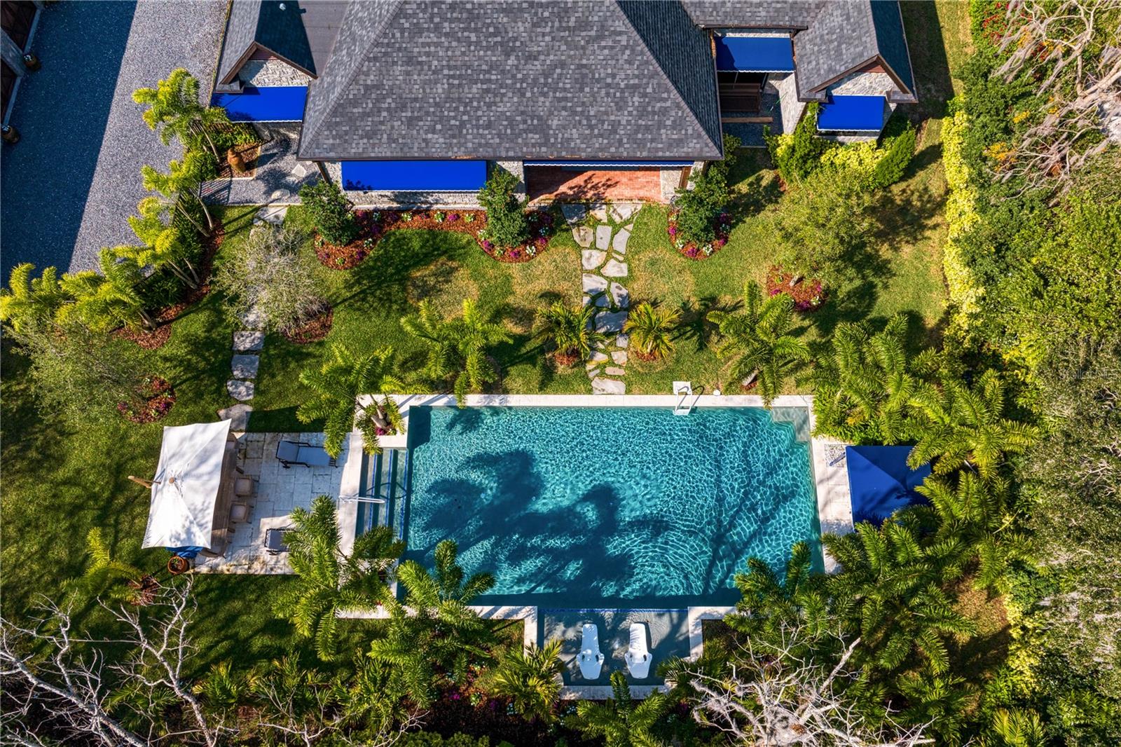 This stunning bird’s-eye view captures a sprawling, immaculate estate, where the vibrant charm of tropical surroundings meets the serenity of an enticing swimming pool.