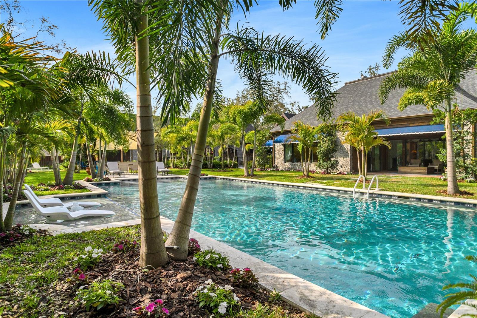 The centerpiece of the estates exterior is a opulent pool framed by swaying palm trees.