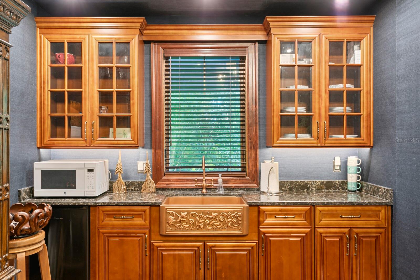 Rich wooden cabinets frame a strikingly detailed, hand-carved sink, creating an inviting focal point that combines elegance with practicality