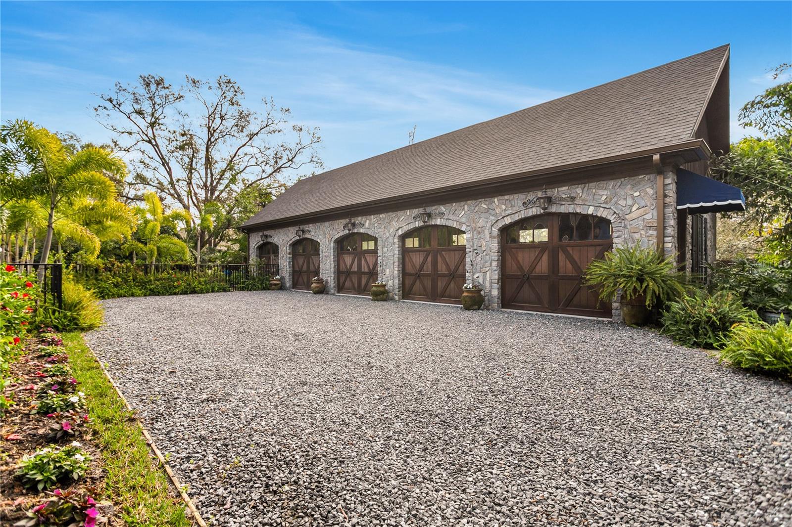 The garage presents a masterclass in craftsmanship with its exquisite stone facade and stately wooden doors, evoking a sense of timeless charm.