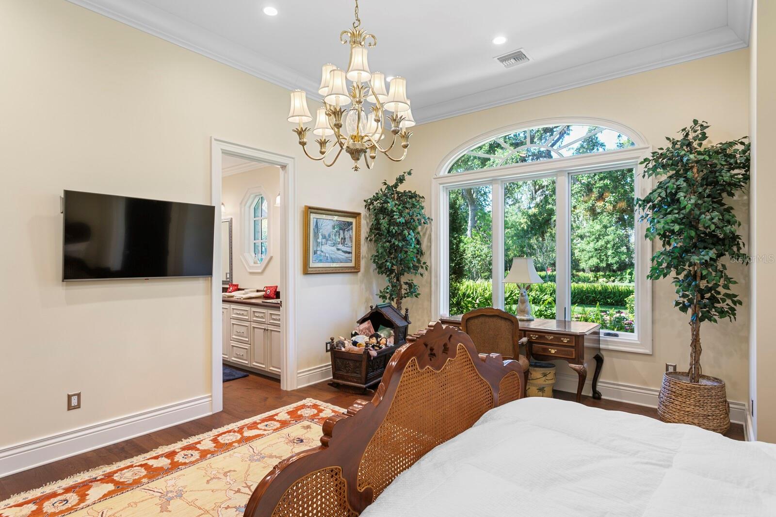 The large, arched window offers a picturesque view of the lush greenery outside, promising the perfect wake-up call each morning.