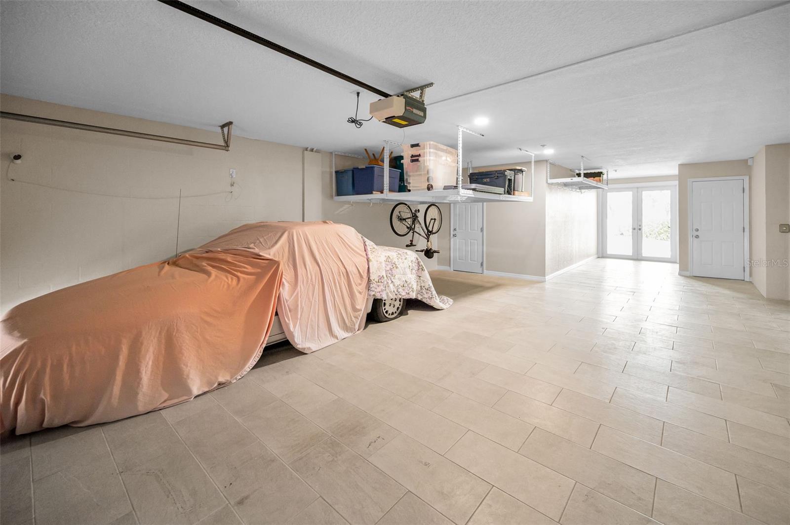 Huge garage! Tile on Floor! Wet-bar is door to left and workshop is door to right. French doors lead to lanai.