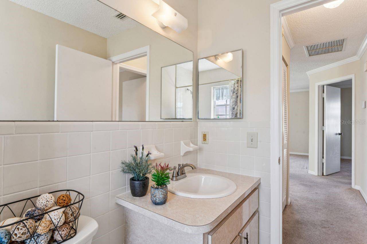 The guest bathroom offers storage in the medicine cabinet and under-sink cabinets, along with a view of the hallway and primary bedroom.