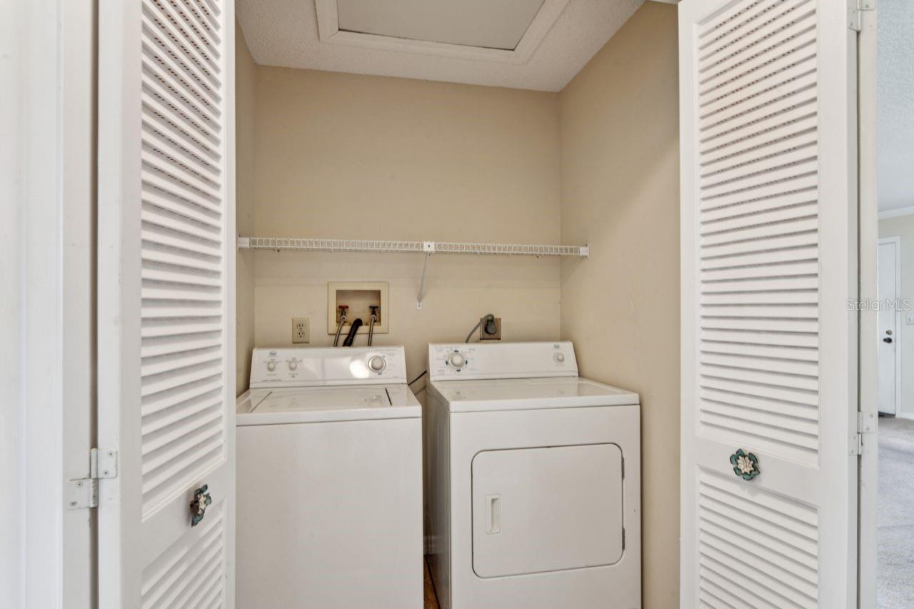 The laundry closet features the washer and dryer, the attic opening with shelving, and louvered doors.