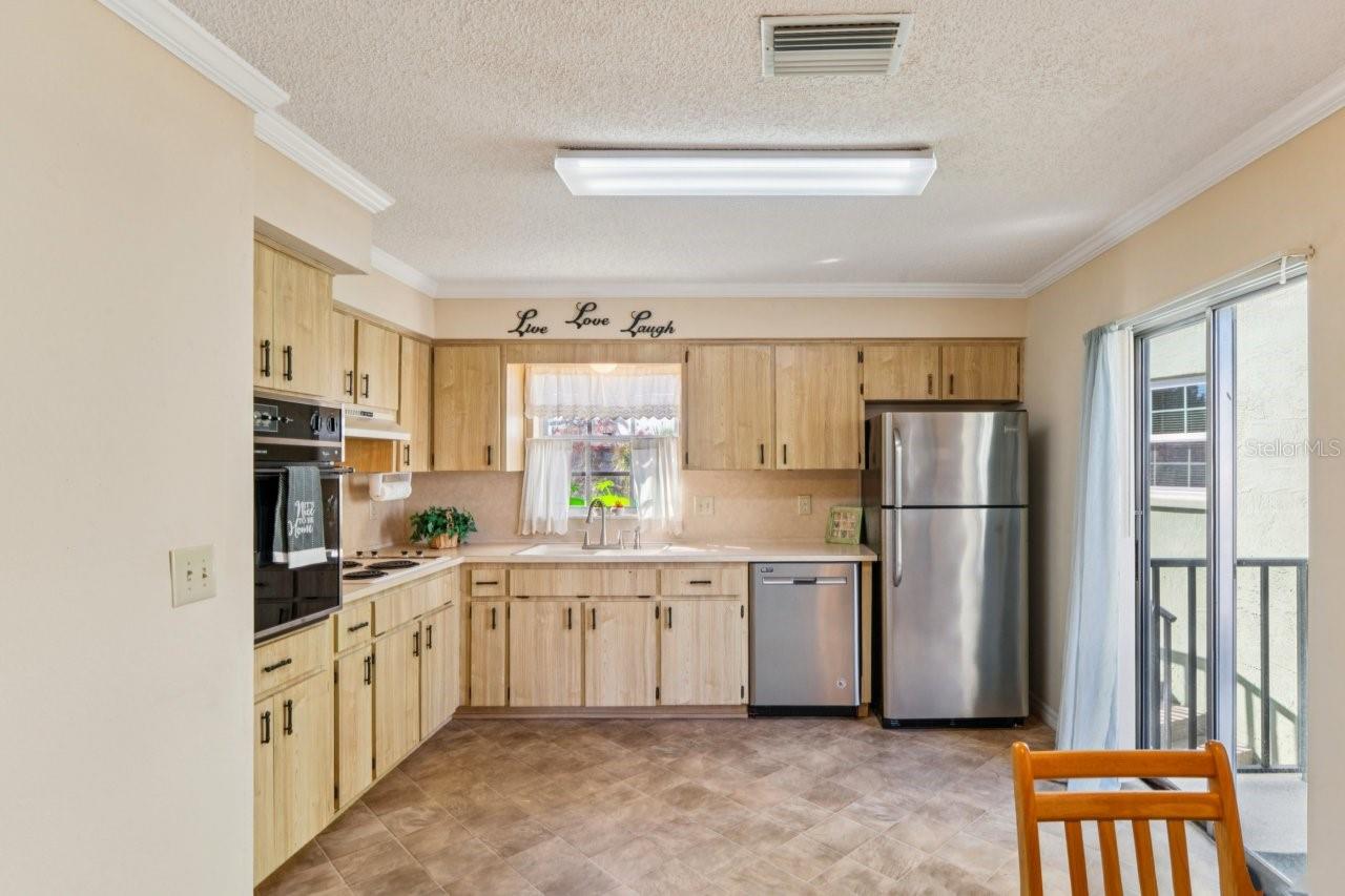 The kitchen features stainless steel appliances, and the sliding door and window let in plenty of light and fresh air.