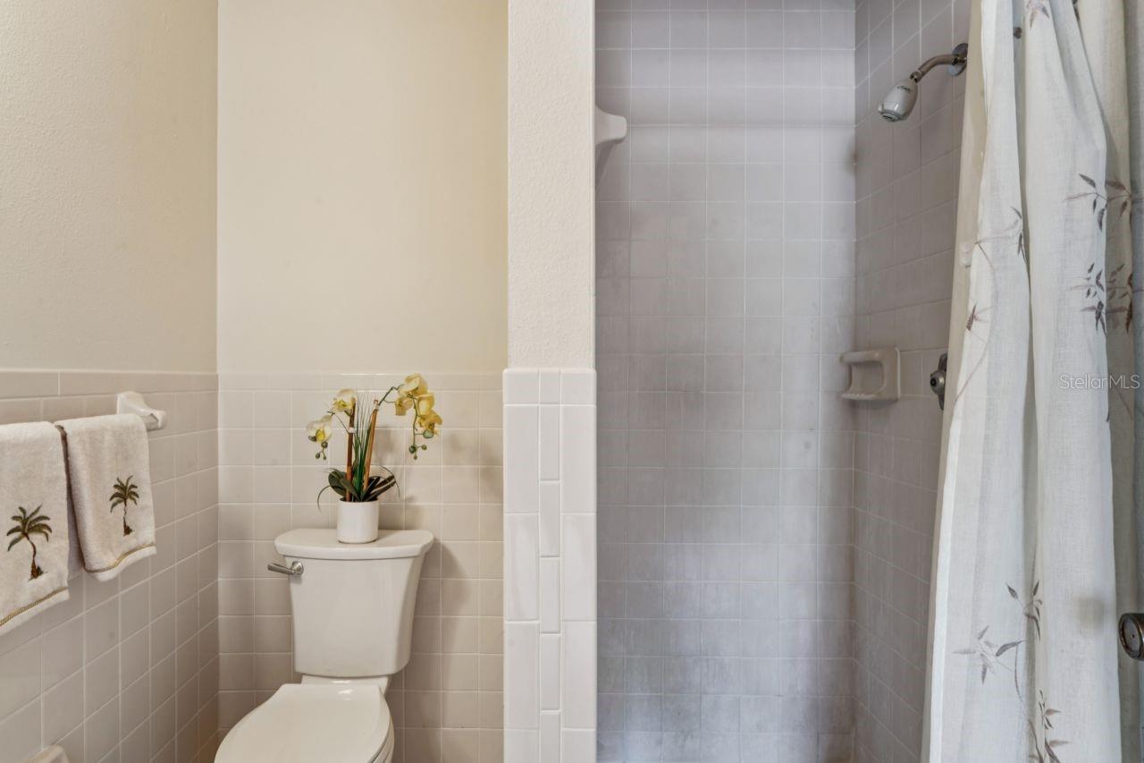 View of the commode and tiled shower.