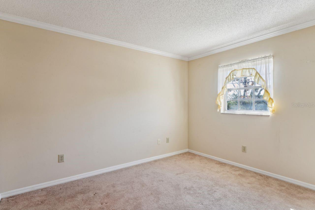 This guest bedroom features cozy carpeting, a beautiful window, elegant crown molding, and convenient cable and internet connections.