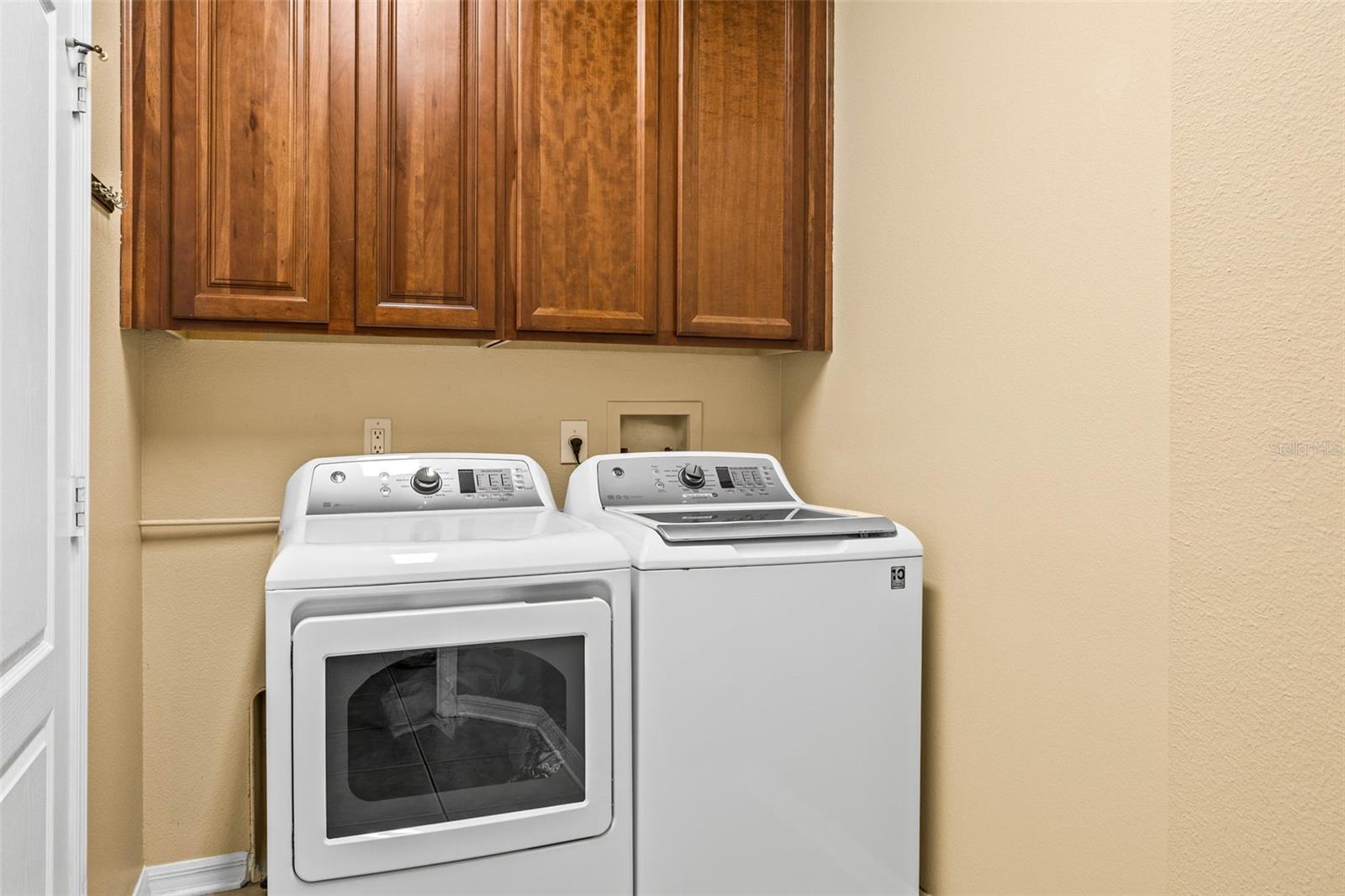 Laundry room beside kitchen with matching cabinetry