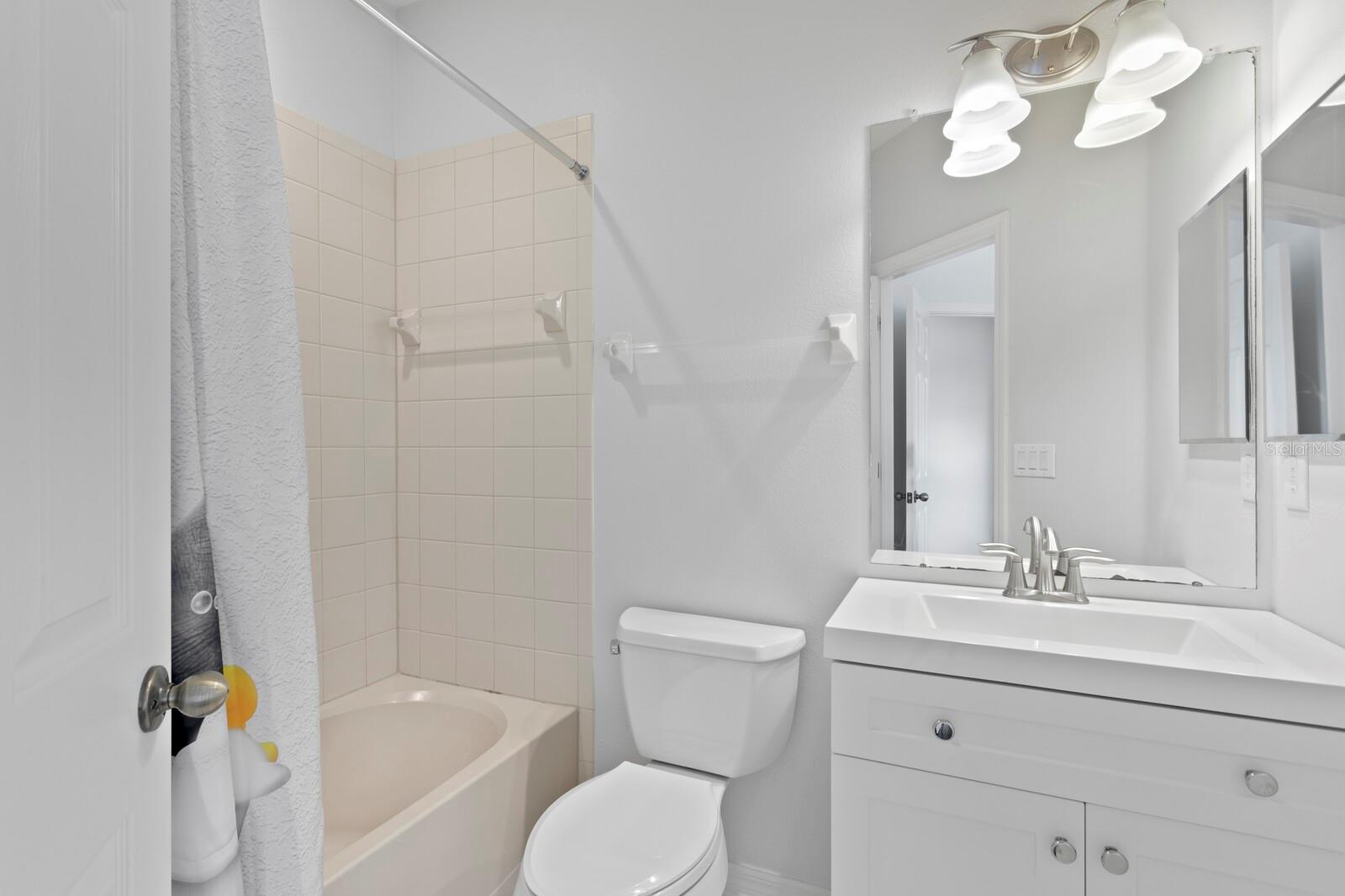 The full ensuite bath in the 2nd bedroom with updated vanity & lighting