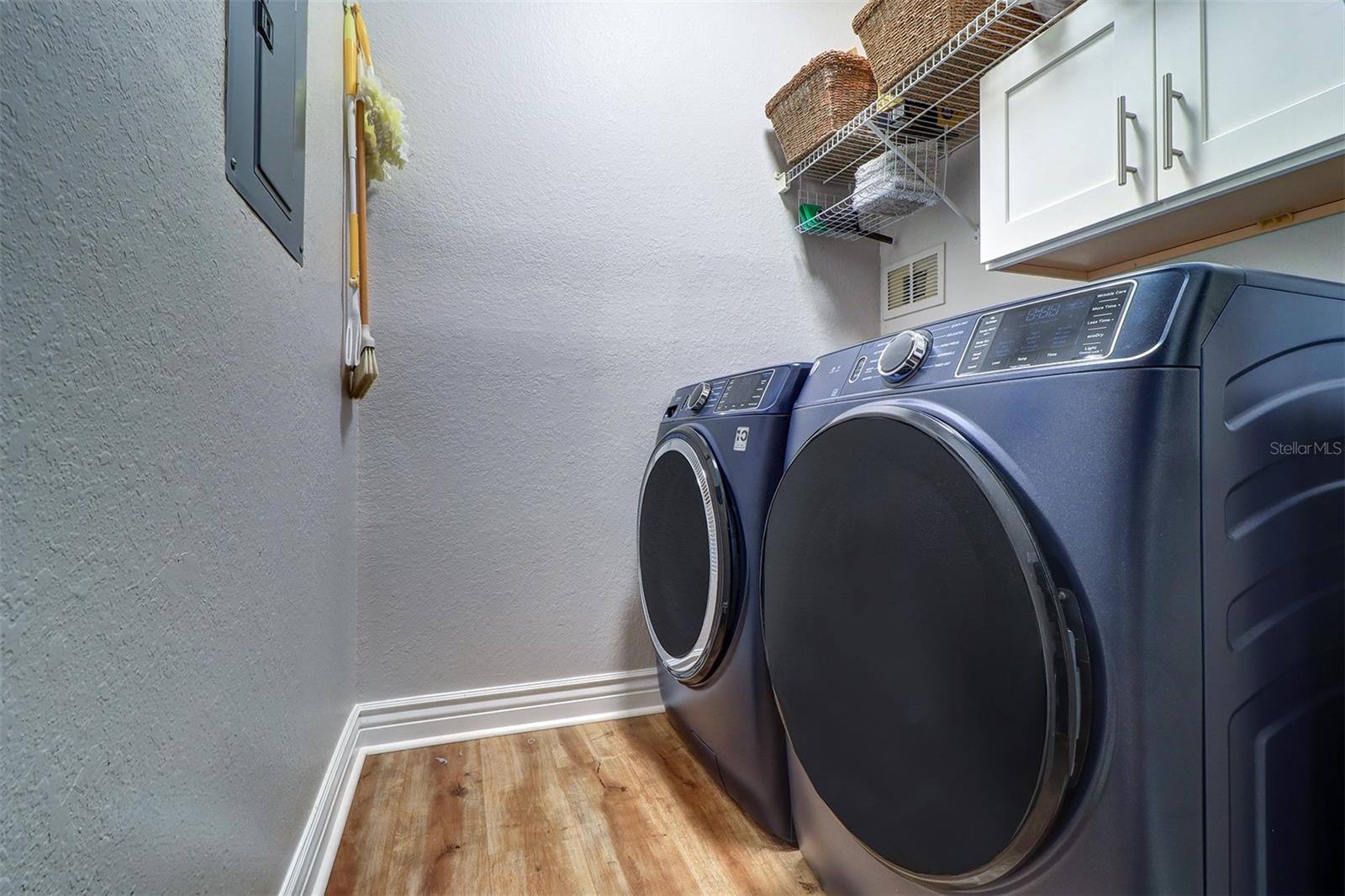Laundry room with full size washer and dryer with shelving and cabinet