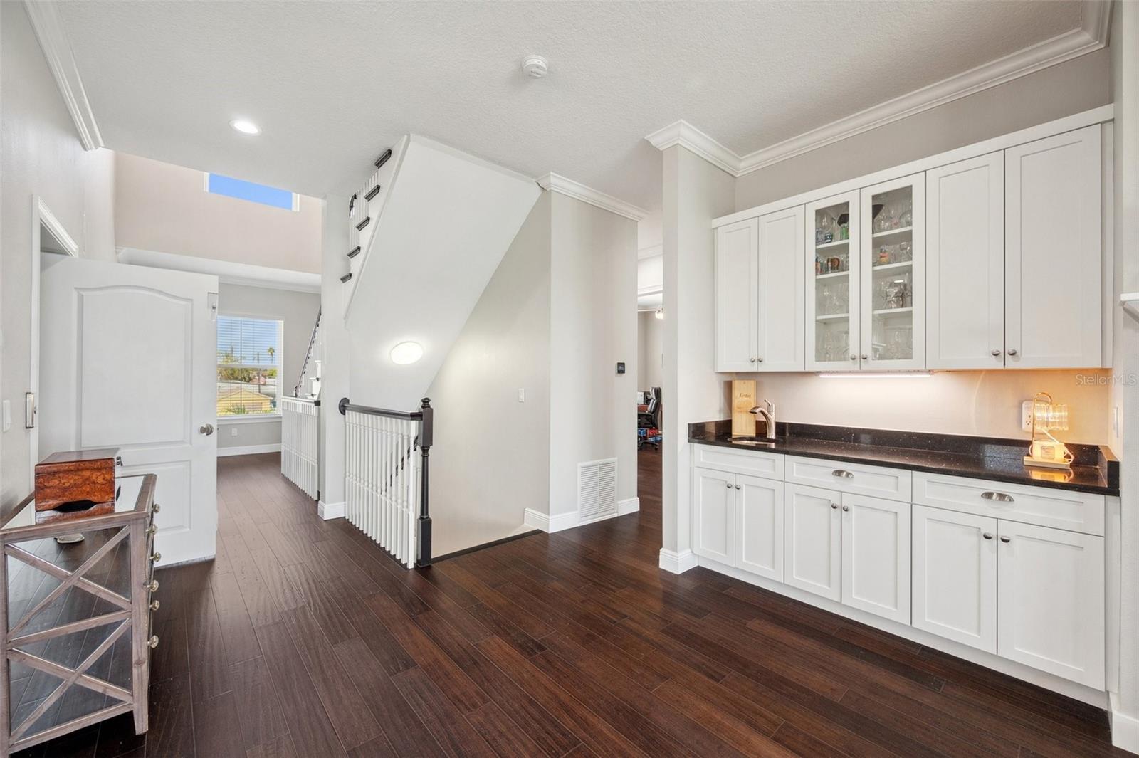 View of wet bar with black granite countertop and custom solid wood cabinetry.