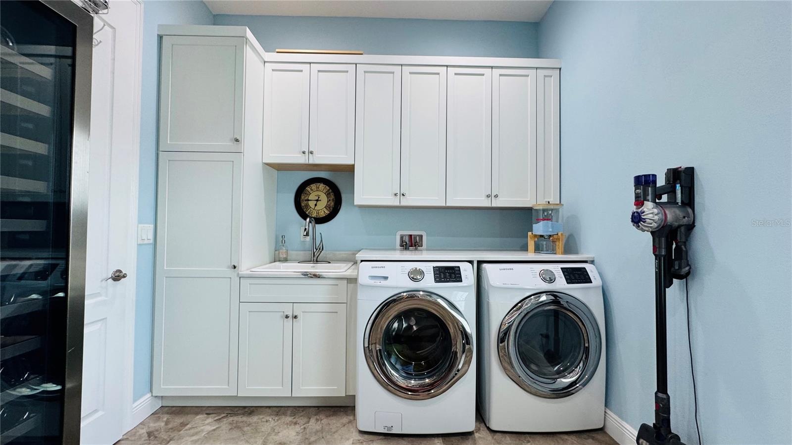 Laundry/pantry room with stone counters, deep laundry sink and custom cabinetry.