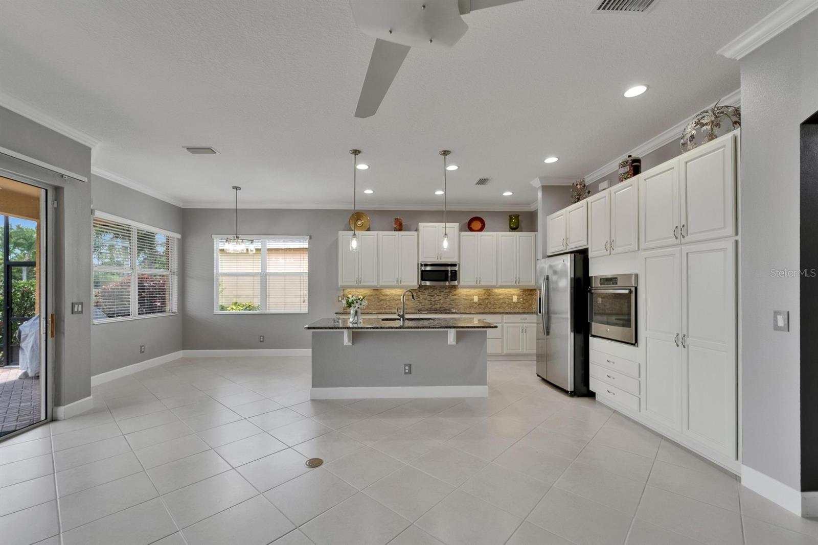 Kitchen features ivory 42” cabinets, trash and recycle receptacle, granite and stainless steel appliances