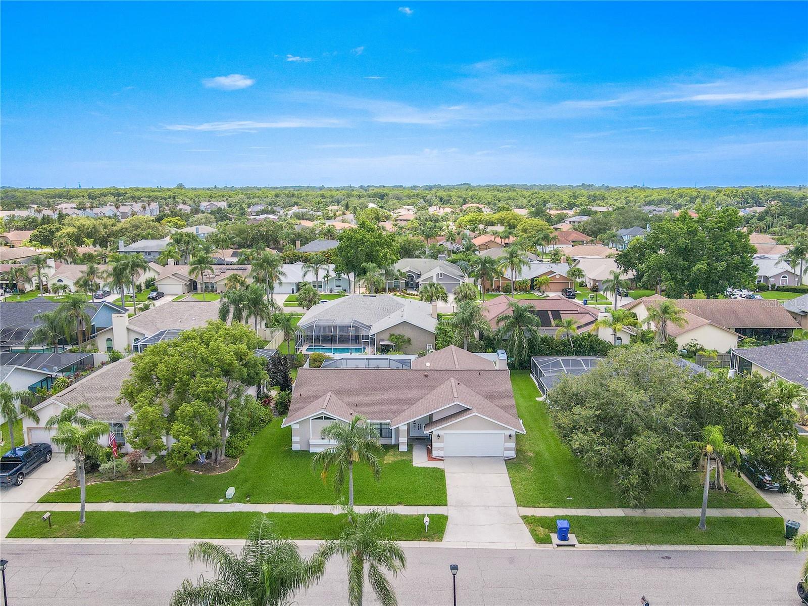 The home's inviting curb appeal draws you in with fresh, neutral tones, crisp white trim, and striking architectural details that add both charm and character.A double-door entry sits beneath a covered front porch, for a stylish and sheltered welcome. The manicured lawn is lush and green, framed by mature palm trees and a wide driveway leading to the spacious two-car garage.