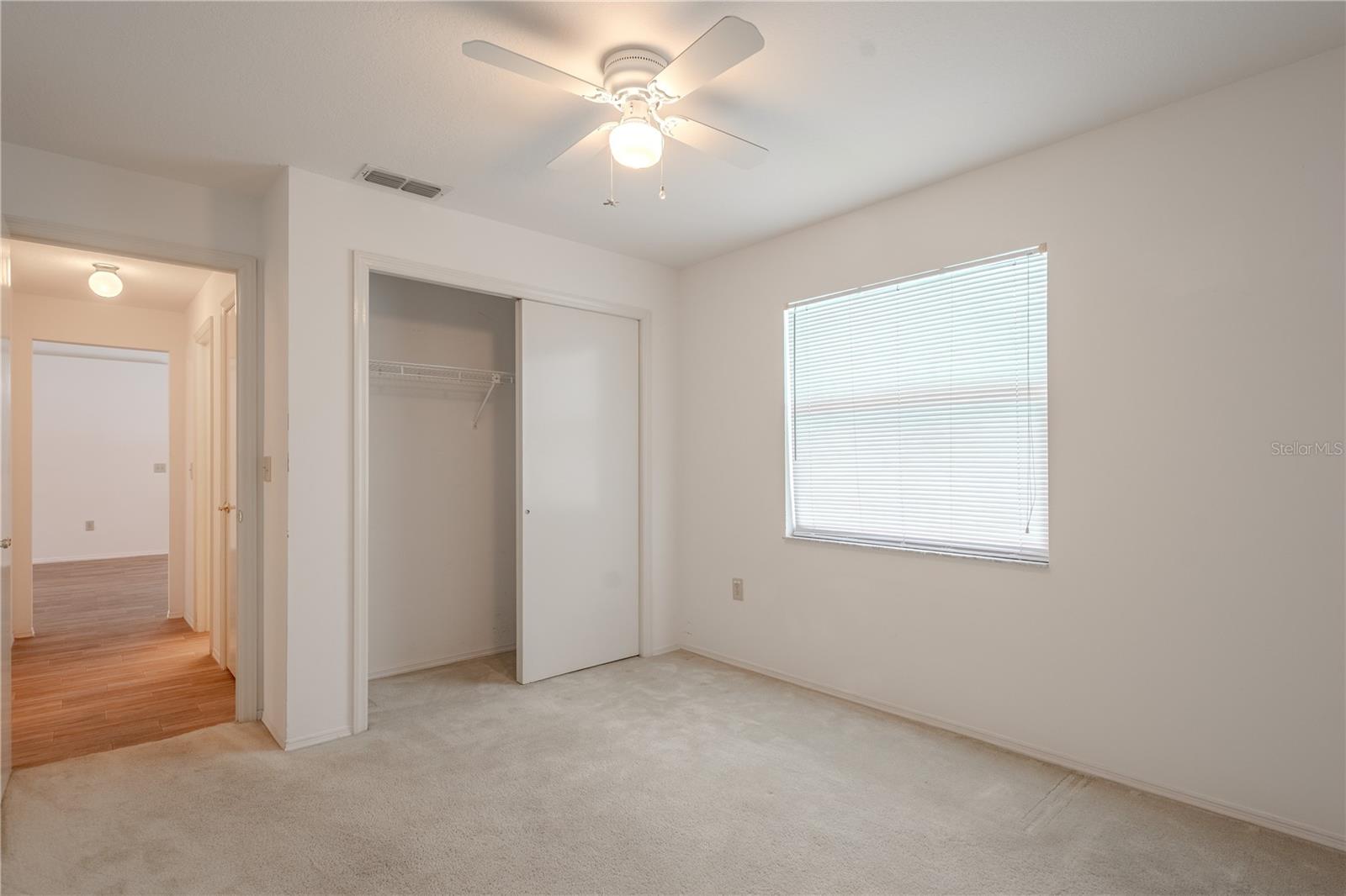 2nd bedroom features a standard-sized closet with sliding doors and built-in shelving, providing practical storage solutions. Neutral walls and flooring make it easy to personalize.