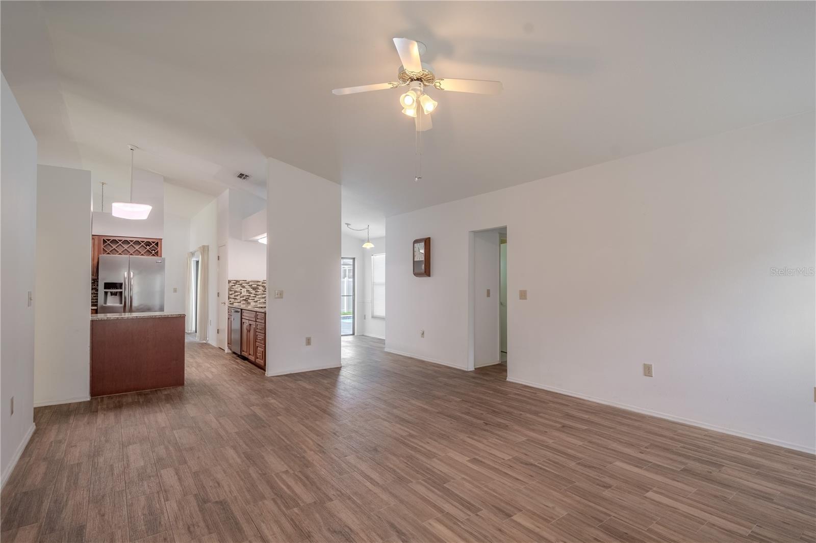 The spacious family room is designed for comfort and connection, offering an open-concept layout with easy flow to the kitchen, breakfast bar, and pool area. Vaulted ceilings enhance the airy feel, while large windows bring in soft natural light throughout the day.