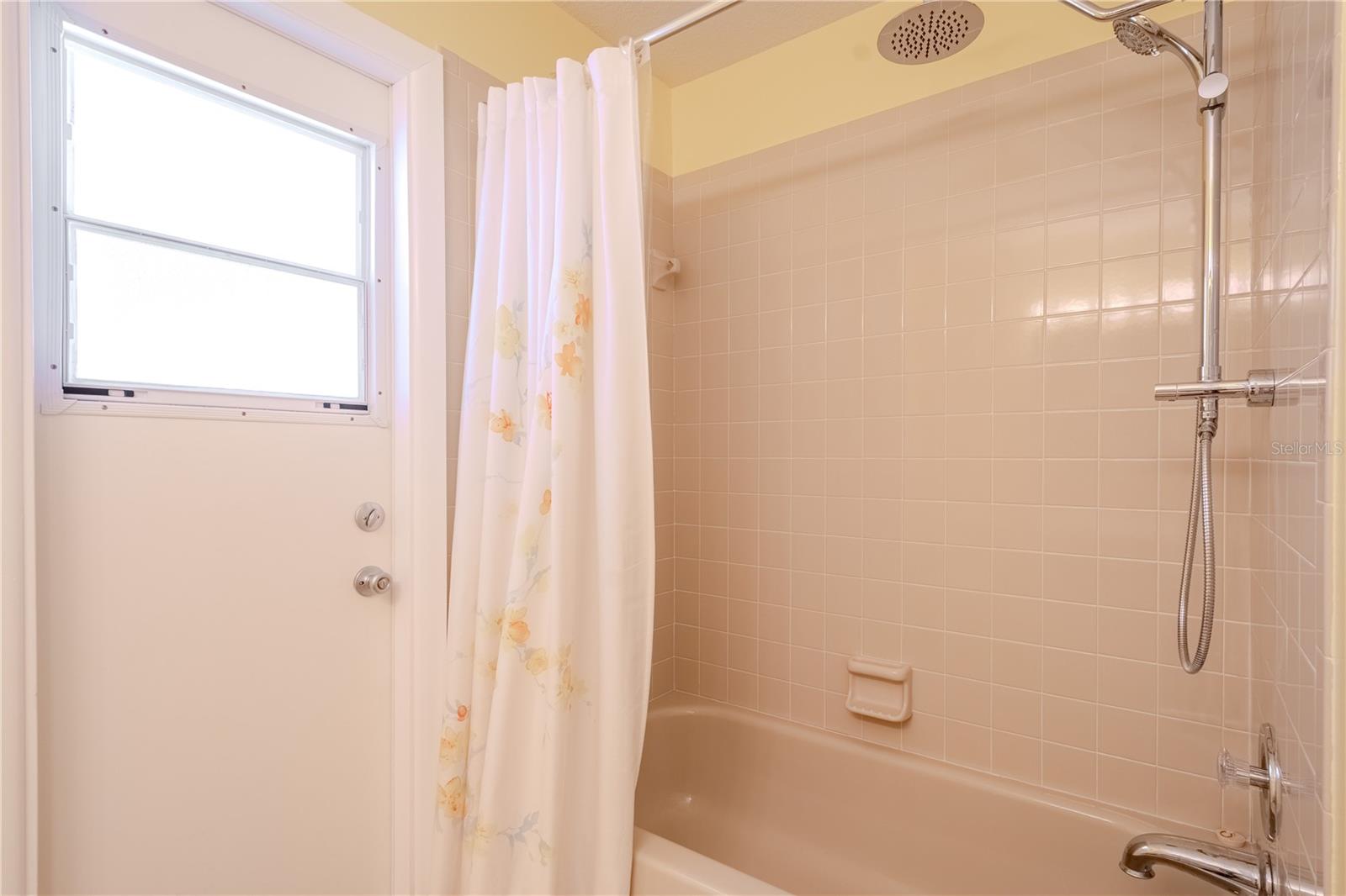 A tub and shower combo with a modern handheld fixture provides versatility, and the dedicated pool door keeps wet feet out of the main living areas.