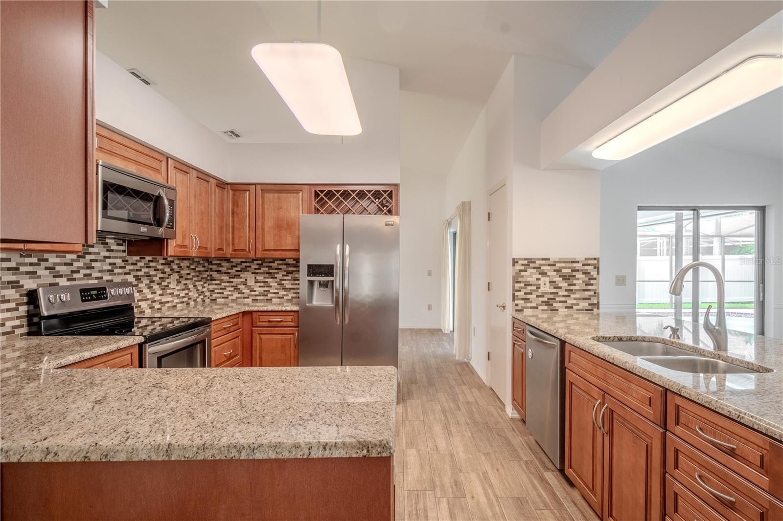 Stainless steel appliances, including a side-by-side refrigerator, oven with a smooth cooktop, built-in microwave, and dishwasher, offer convenience for everyday cooking and entertaining. A built-in wine rack adds a touch of sophistication, while the generous prep space and dual basin sink make meal prep a breeze.