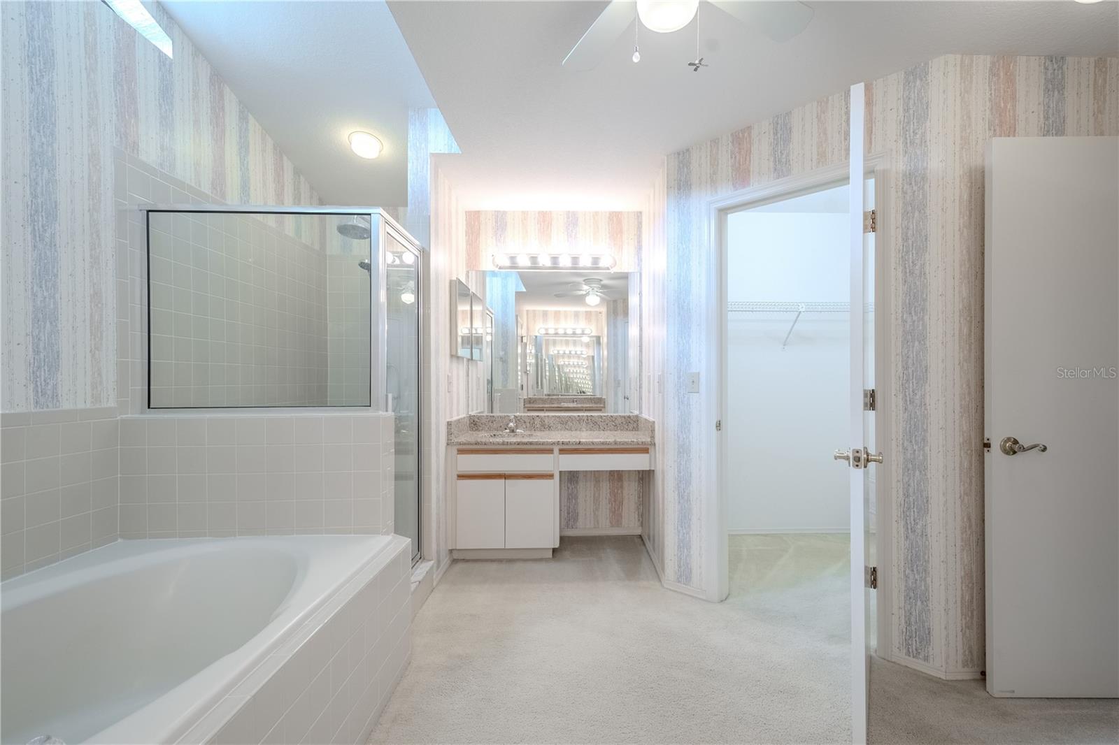 The spacious primary bathroom offers a functional layout with everything you need for daily comfort and convenience. A deep soaking tub sits beneath a dramatic transom window that floods the space with natural light, creating a serene setting for unwinding at the end of the day.