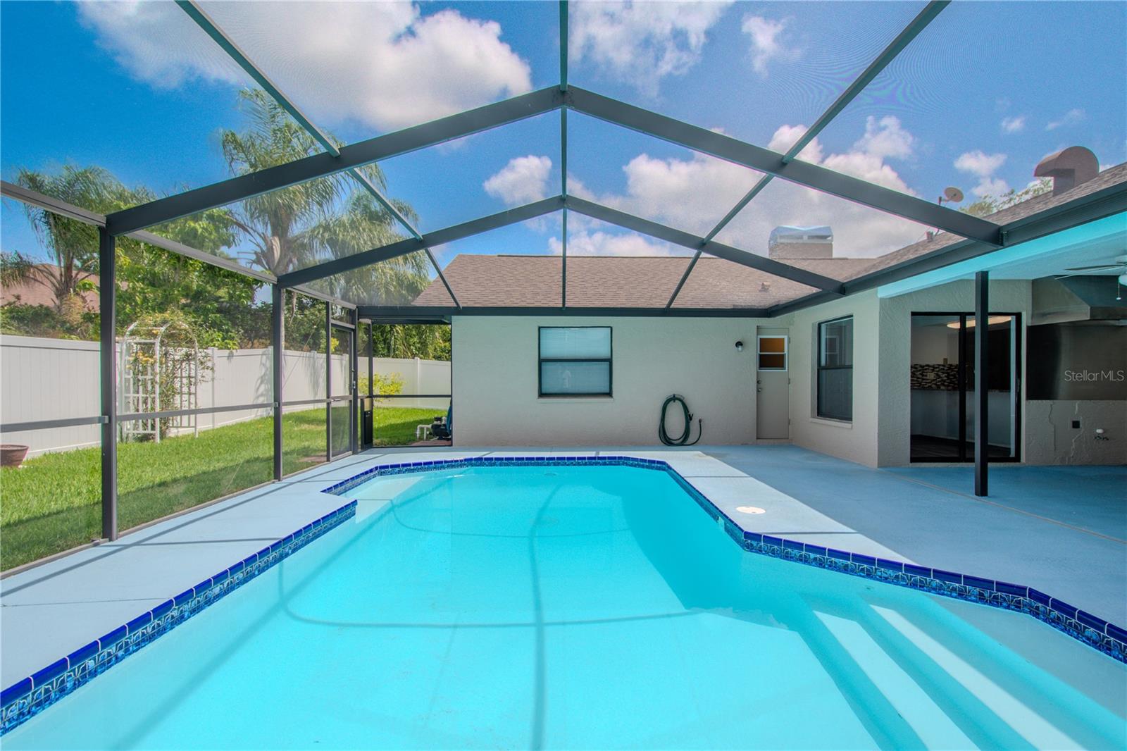 The sparkling pool invites a refreshing dip, framed by the pool deck and surrounded by a brand-new privacy fence (installed 2025) for added peace of mind and seclusion.
