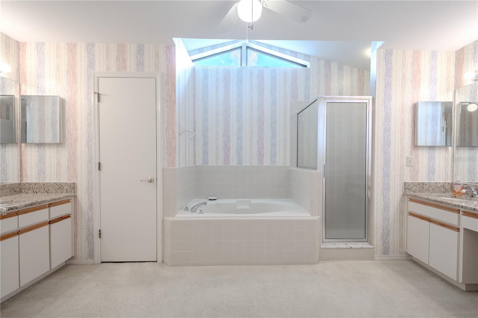 Primary Bath separate walk-in shower provides added versatility, while dual granite-topped vanities offer ample counter space and storage for busy mornings. A dedicated water closet adds privacy