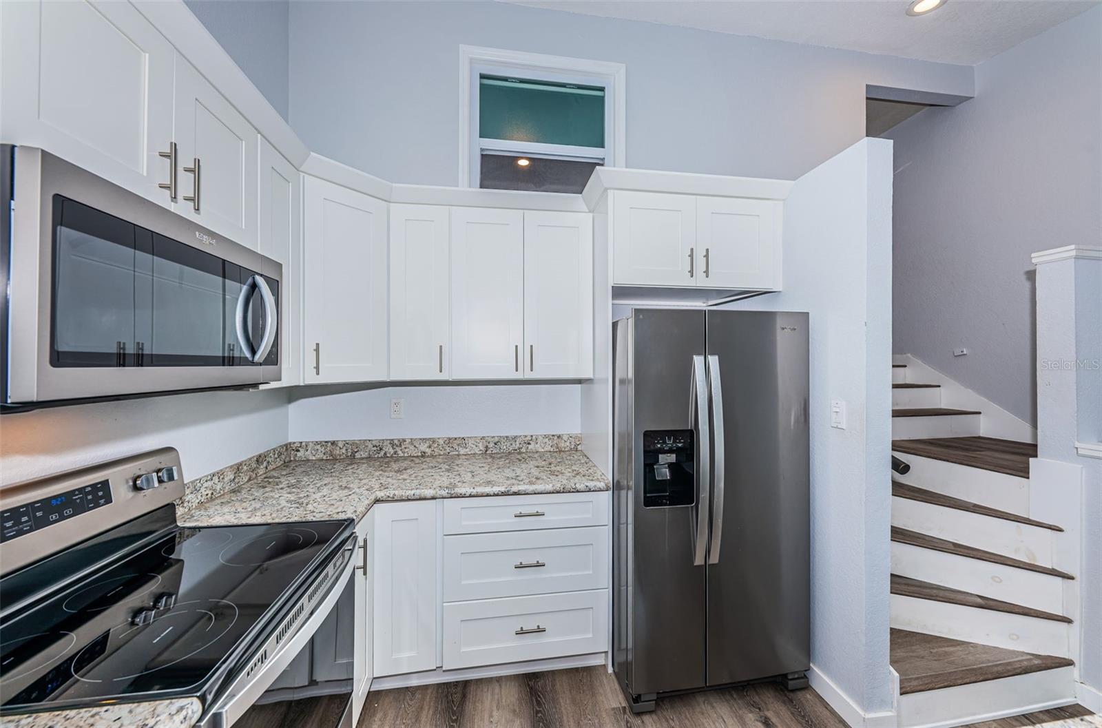 Kitchen w/ stairs leading to the bedrooms/bathrooms, note 2nd bedroom window overlooking the main living area