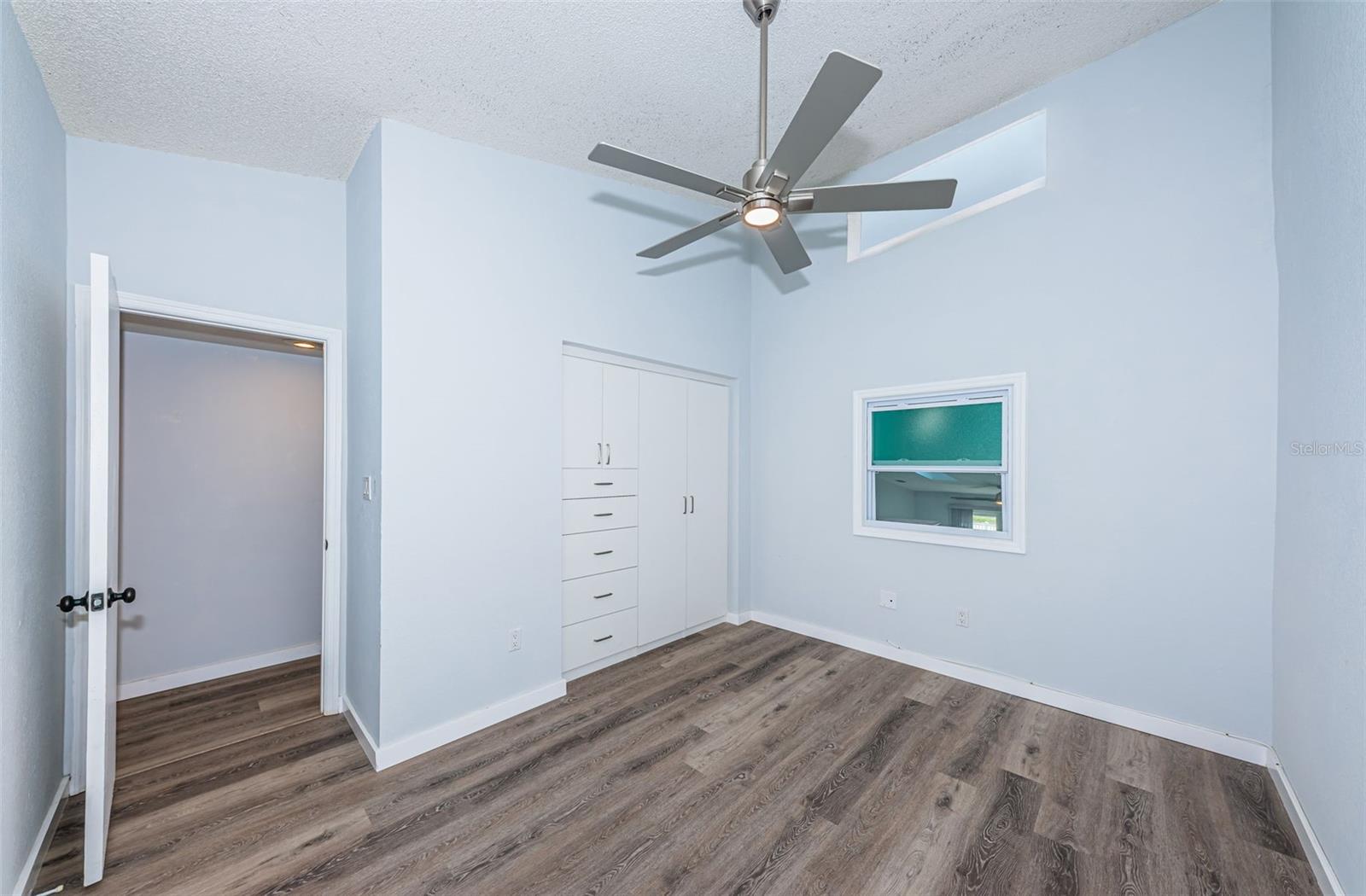 2nd/guest bedroom w/ newer fan, closet/drawers, window overlooking the main area & a clerestory window (has a velcro shade)