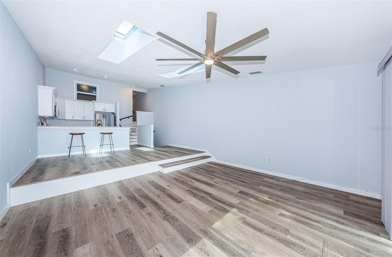 Great room, dining area, kitchen & stairs going up to the bedrooms/bathrooms, note the newer fan, skylights w/ blinds & recessed lighting