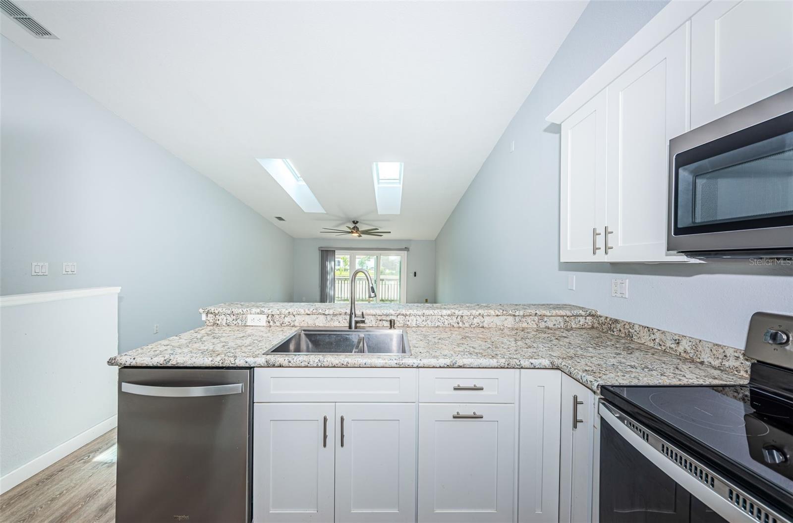Kitchen dishwasher, double sink, trash bin, looking toward the rear porch impact sliders