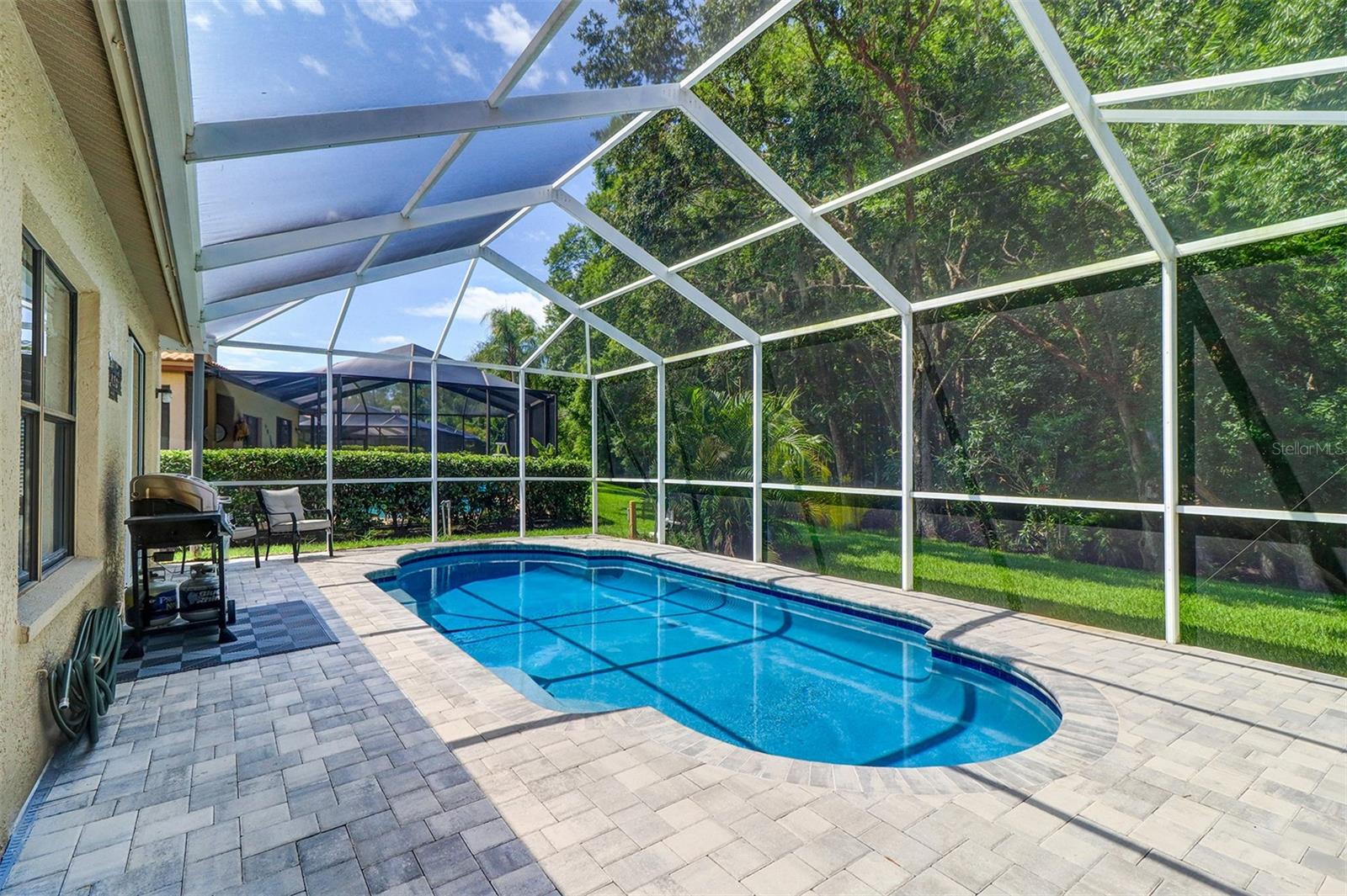 New paver decking surrounding renovated inground pool with screened enclosure