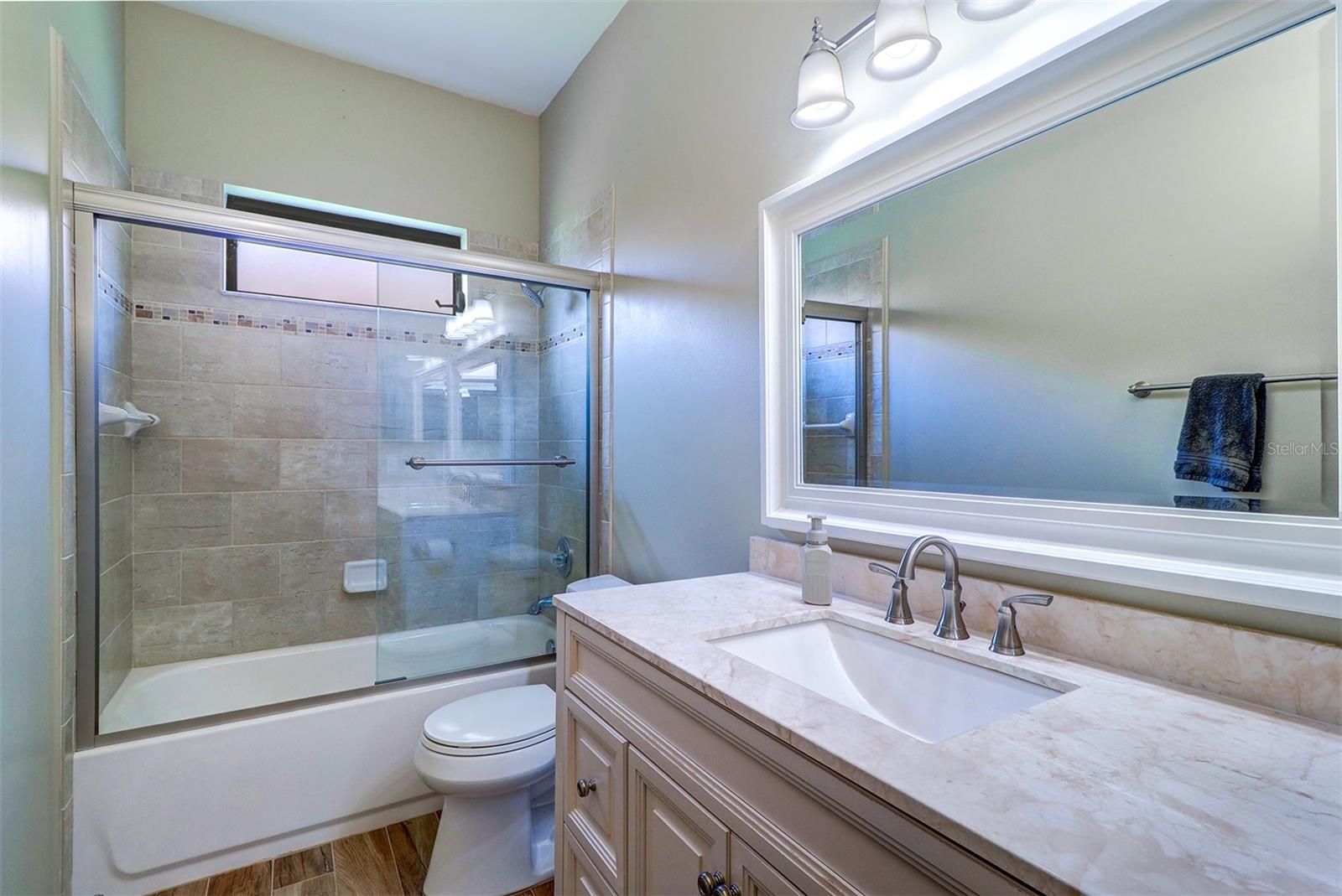 Guest or hall bath with single vanity, tiled shower and tub combination, tile floor