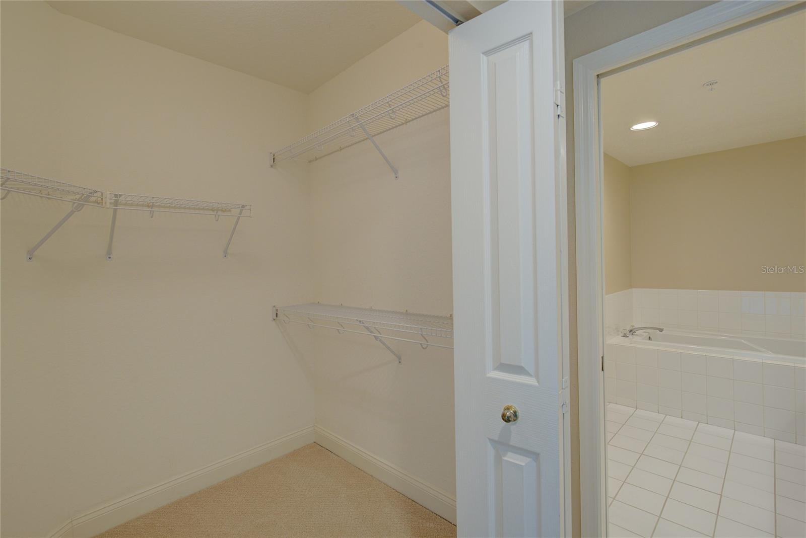 Large walk in closet in the primary bedroom with a large large for him on the other side.