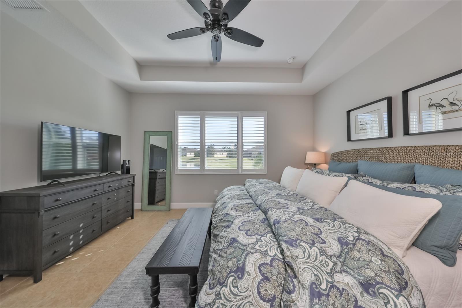 Owner's suite with neutral 'coastal' colors, trey ceilings and a large window with a water view.