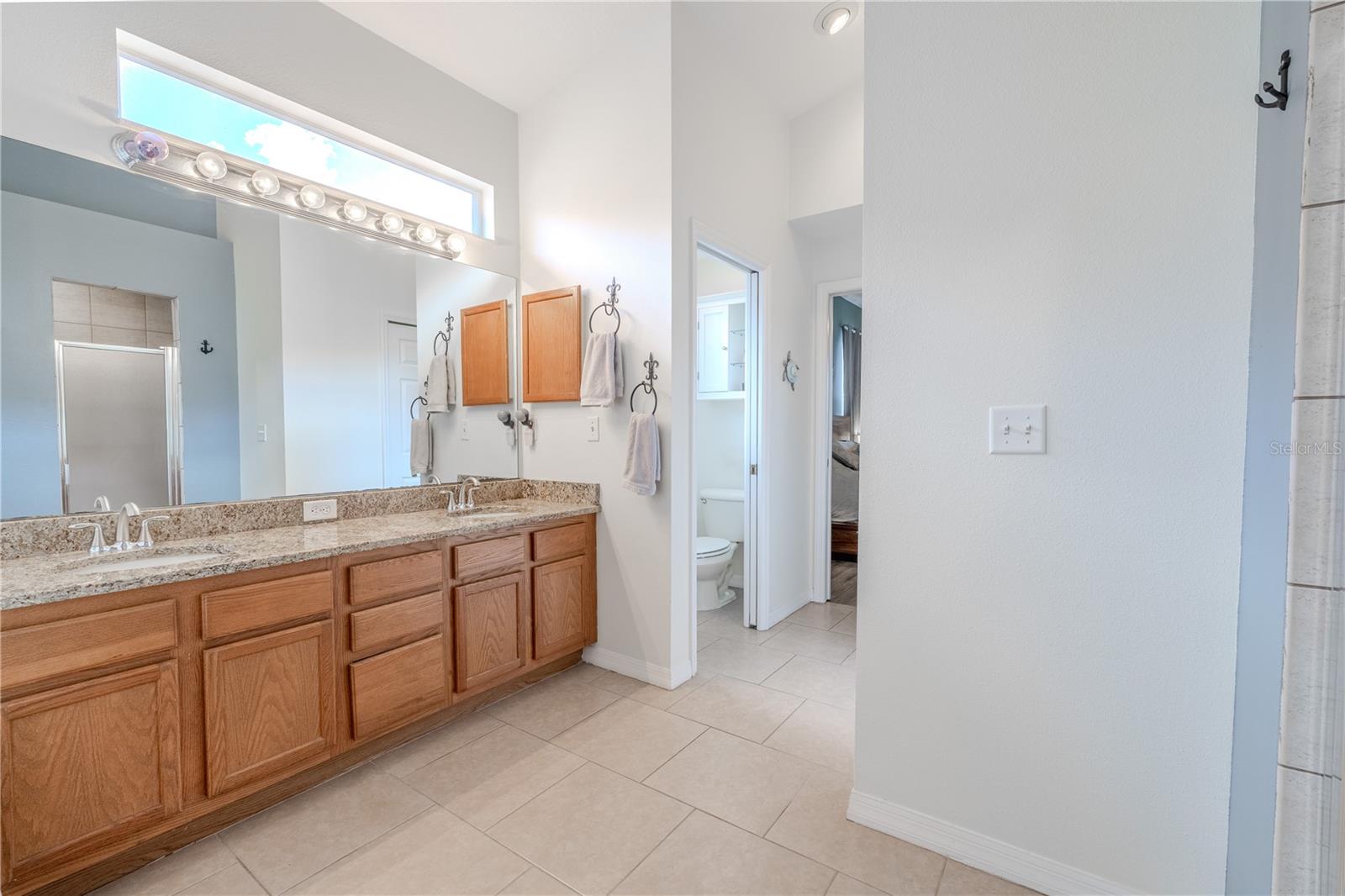 The en-suite bath feels like a personal spa, complete with dual vanities, granite countertops, a garden soaking tub, walk-in shower, private water closet, and plenty of storage.