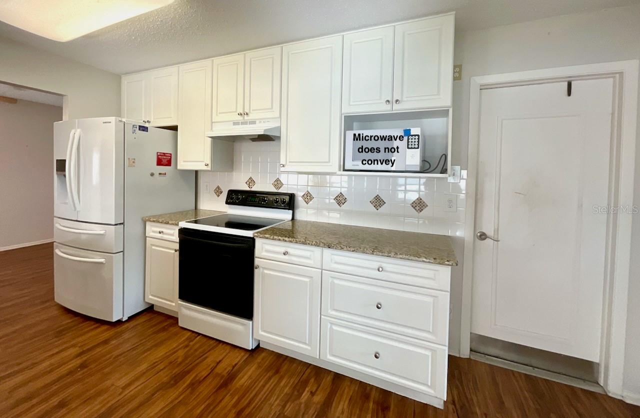Kitchen range side with door to garage. Microwave does not convey.