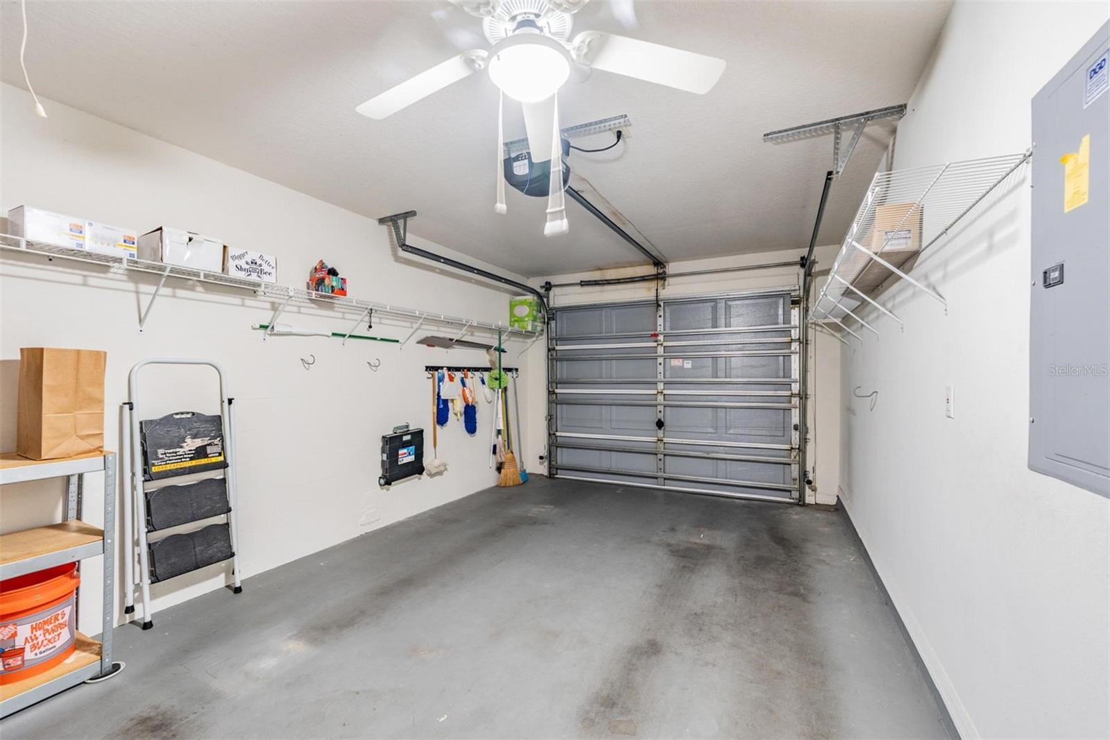 One car attached garage, ceiling fan with light and storage shelves.