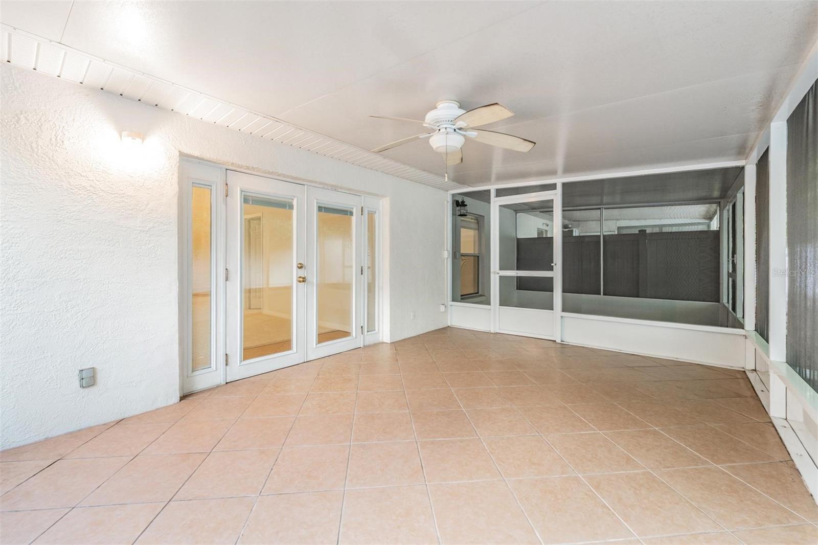 Large back Patio with a ceiling fan and tile flooring ( additional screened in patio on the left)