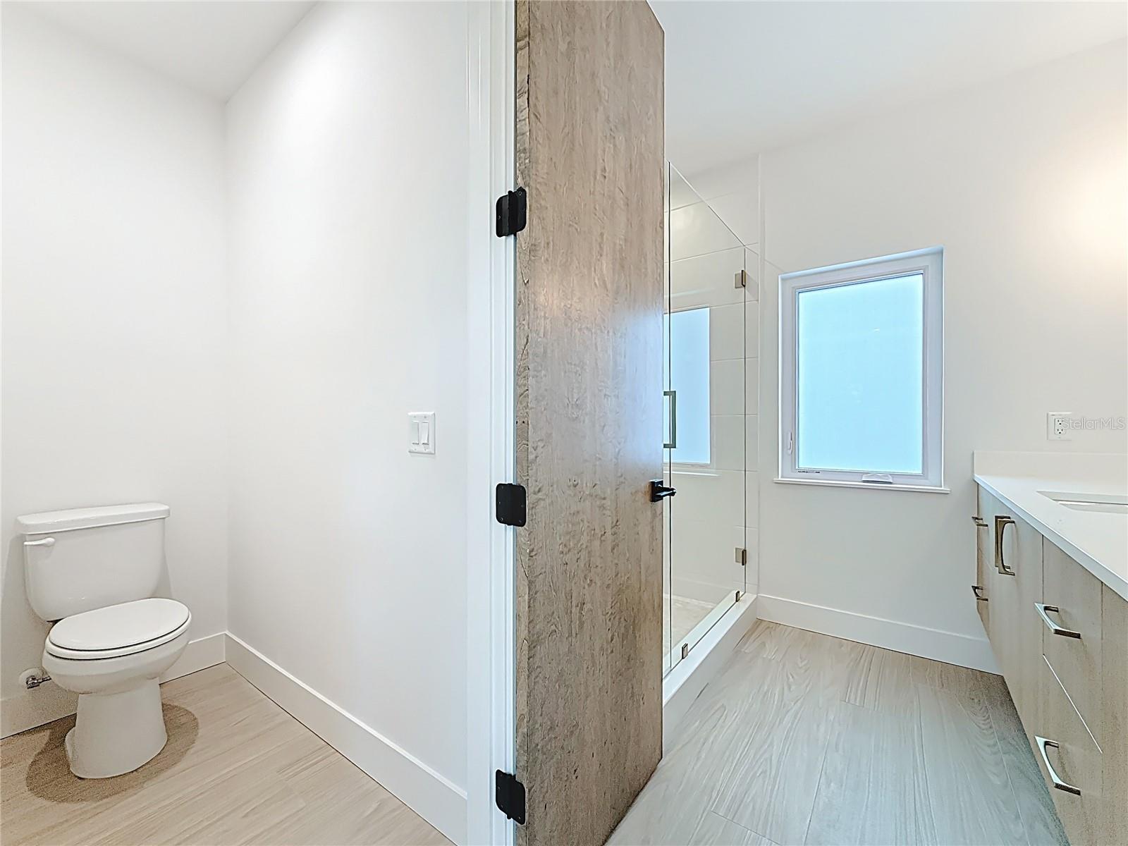 Spa-like en-suite bath featuring dual sinks, an oversized walk-in shower, and a private water closet.