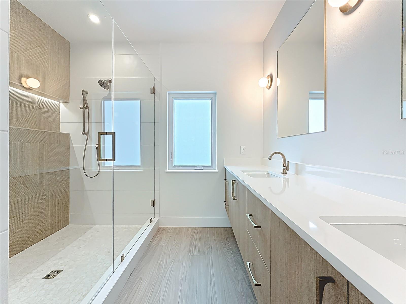 Spa-like en-suite bath featuring dual sinks, an oversized walk-in shower, and a private water closet.