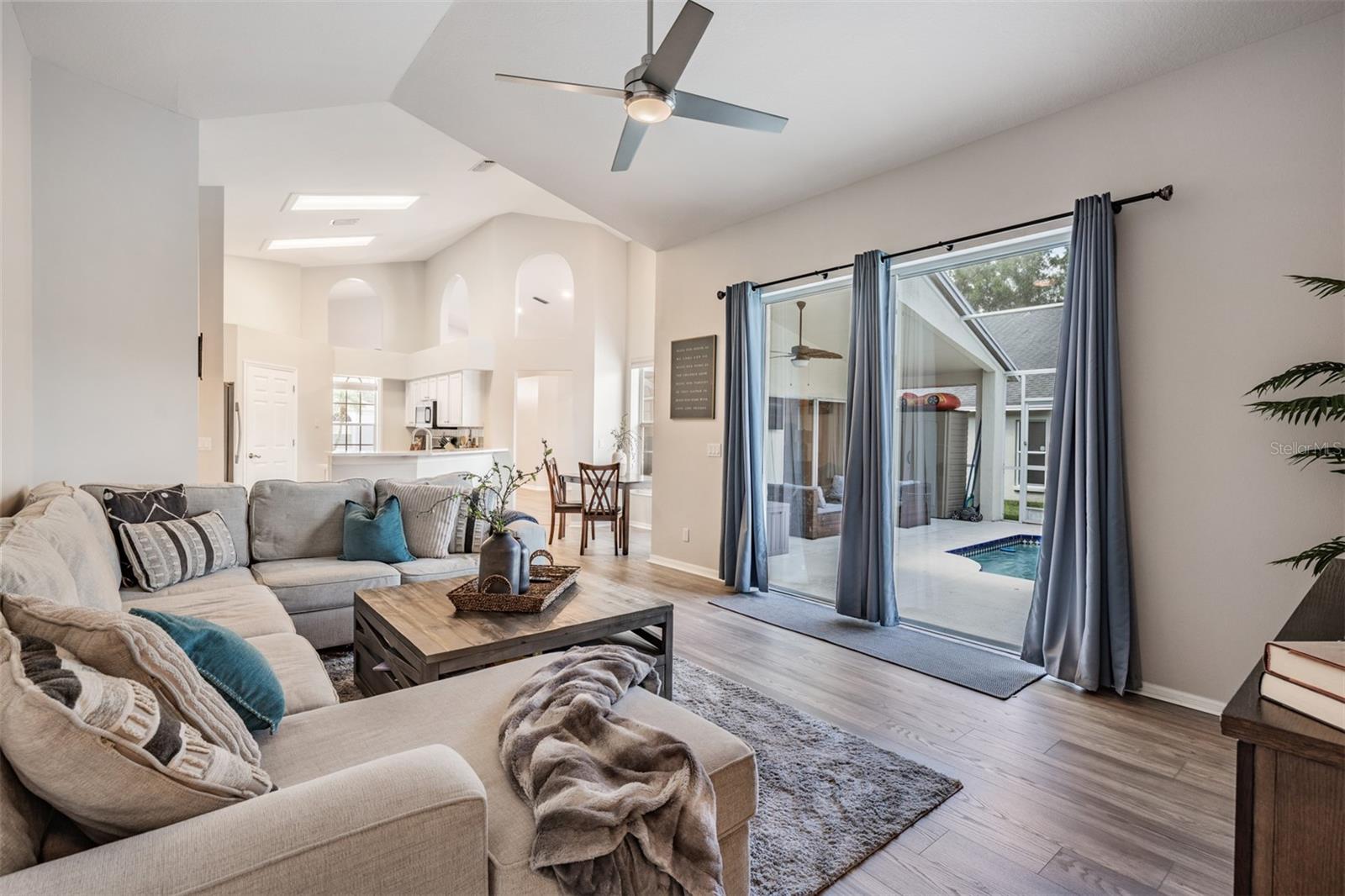 Large Great Room, vaulted ceilings, New Flooring and Ceiling fan with light fixture, overlooking the pool/lanai.