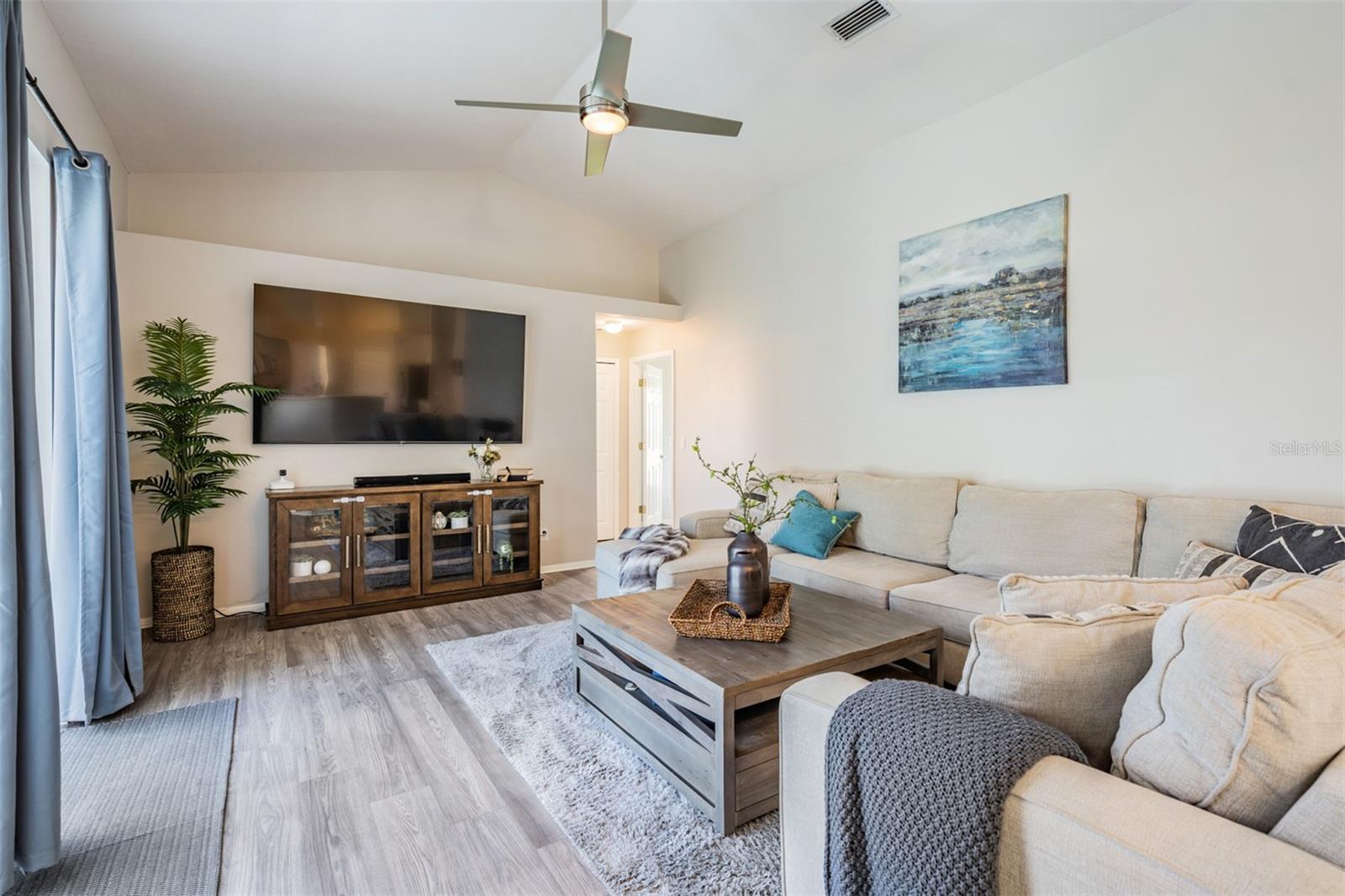 Large Great Room, vaulted ceilings, New Flooring and Ceiling fan with light fixture, overlooking the pool/lanai.