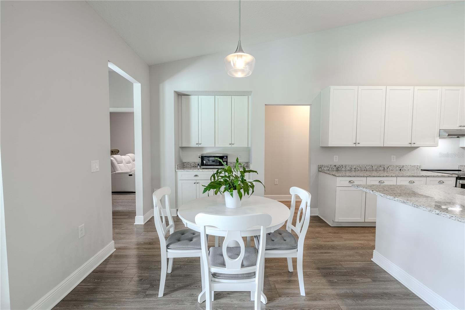 This cozy dining area is perfectly positioned off the kitchen, featuring wood-look flooring, neutral tones, and a modern pendant light. Built-in cabinetry with granite countertops provides additional storage and serving space, while the open layout allows for easy access to the kitchen and nearby living areas. Ideal for casual meals or morning coffee, this space combines functionality with charm.