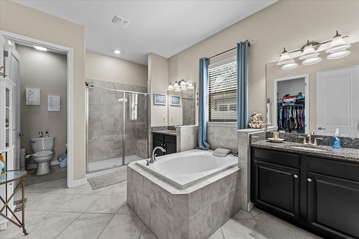 Master Bathroom with his and her sinks, shower bench, soaking tub, bidet in the water closet